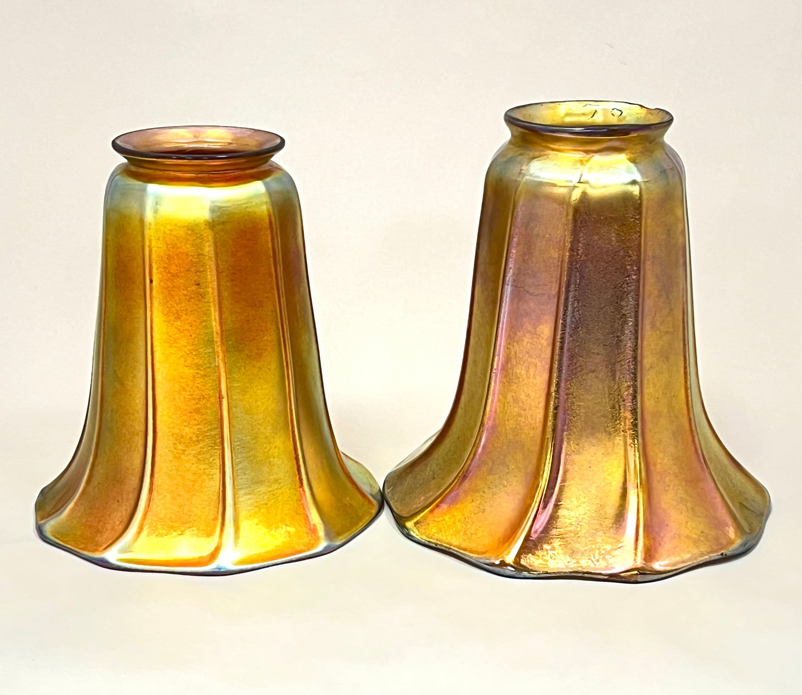 Pair of Gold Aurene shades: Pair of ribbed Gold Aurene shades with red overtones attributed to Steuben, tallest 5 3/4" ht. CONDITION: no chips, cracks, repairs or material defects found. Jaremos attempts to call any material fla