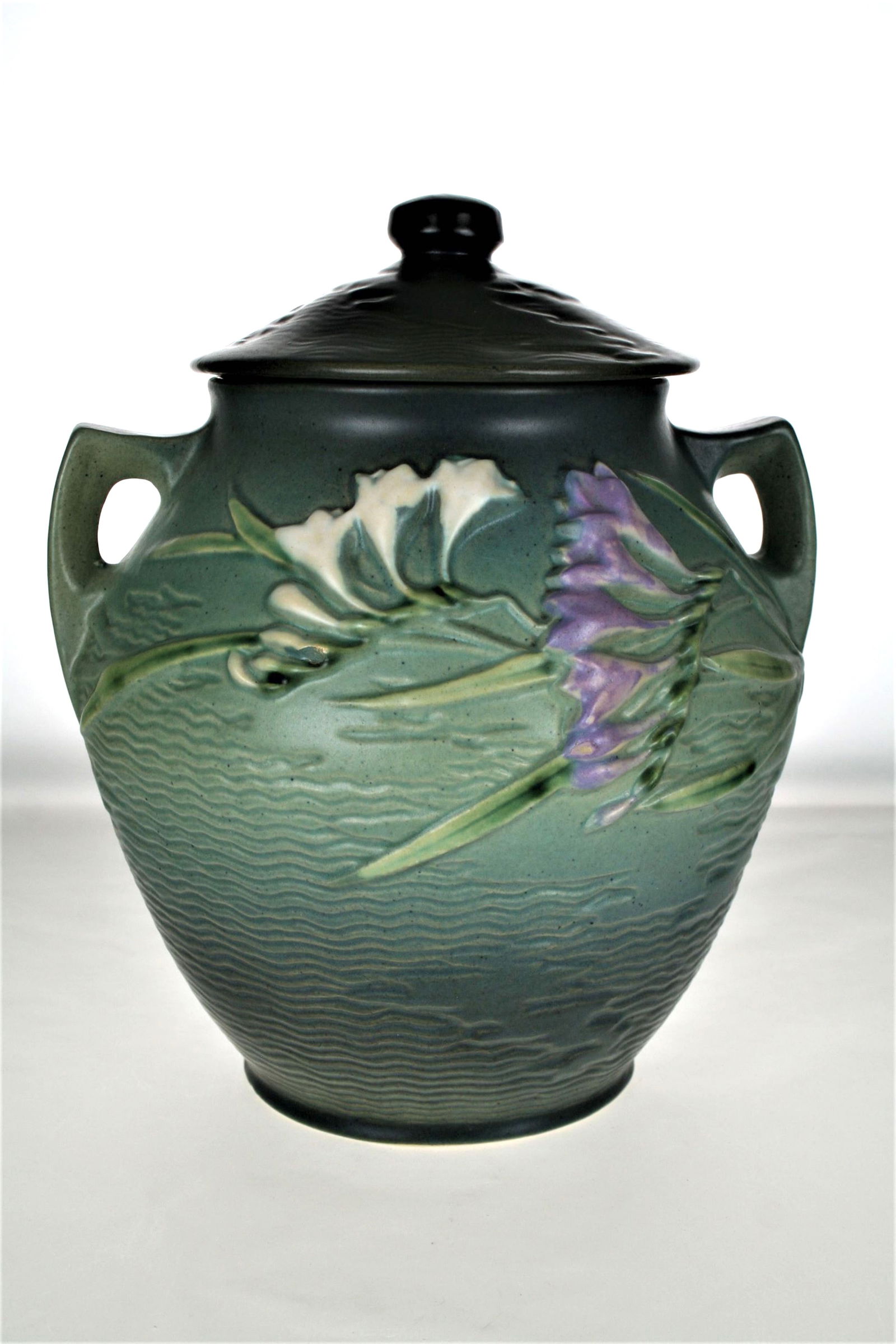 Roseville Freesia pottery cookie jar: Roseville Freesia green cookie jar with lid, 9 1/2" ht. CONDITION: no chips, cracks, repairs or material defects found. Jaremos attempts to call any material flaw that affects the price, but minor scr