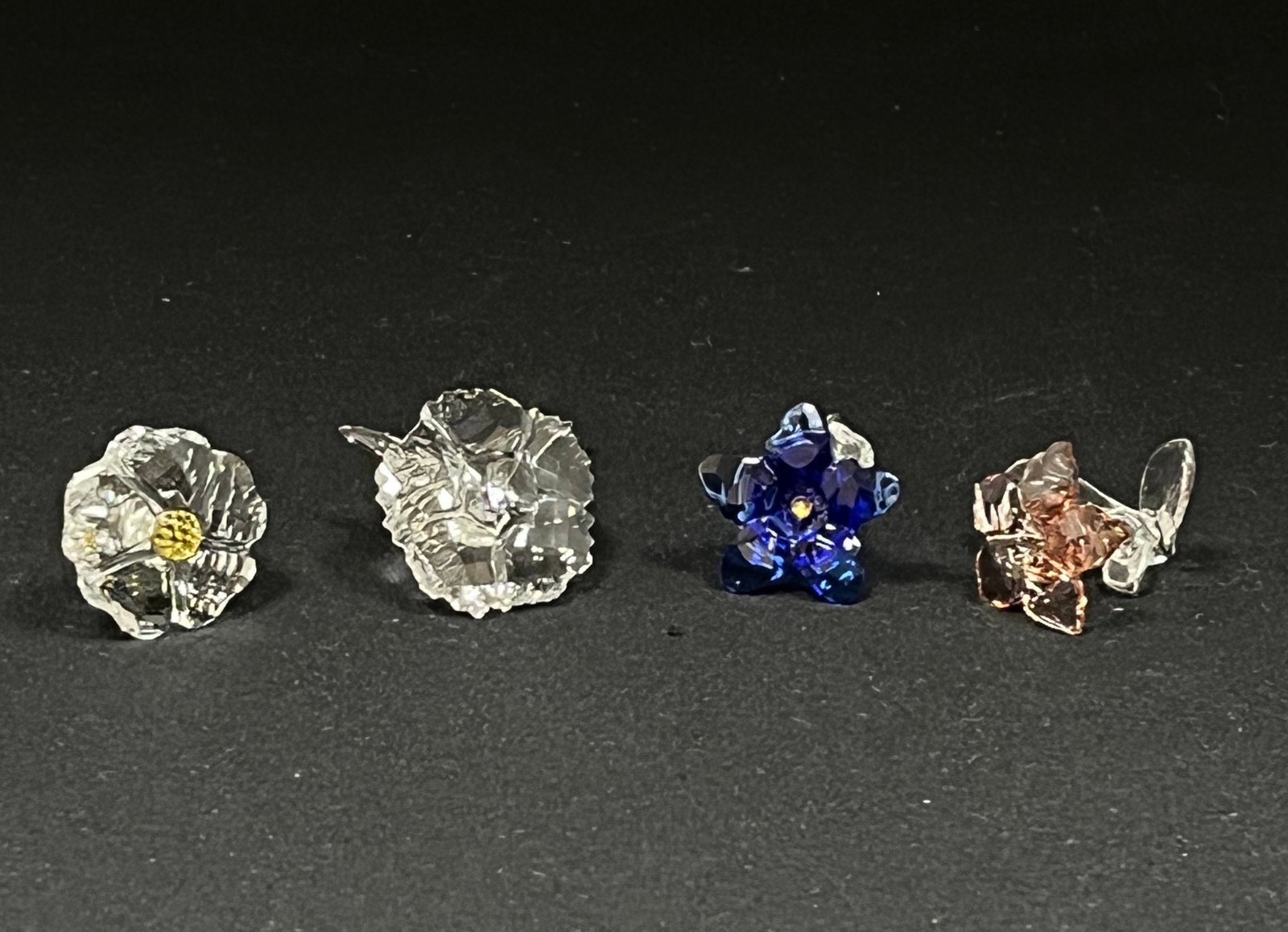 Four Swarovski flowers: Four Swarovski flowers with gift box, including a pink desert rose, amur, gentian, and a wild flower, all approx, 2" long. CONDITION: no chips, cracks, repairs or material defects found. Jaremos attem