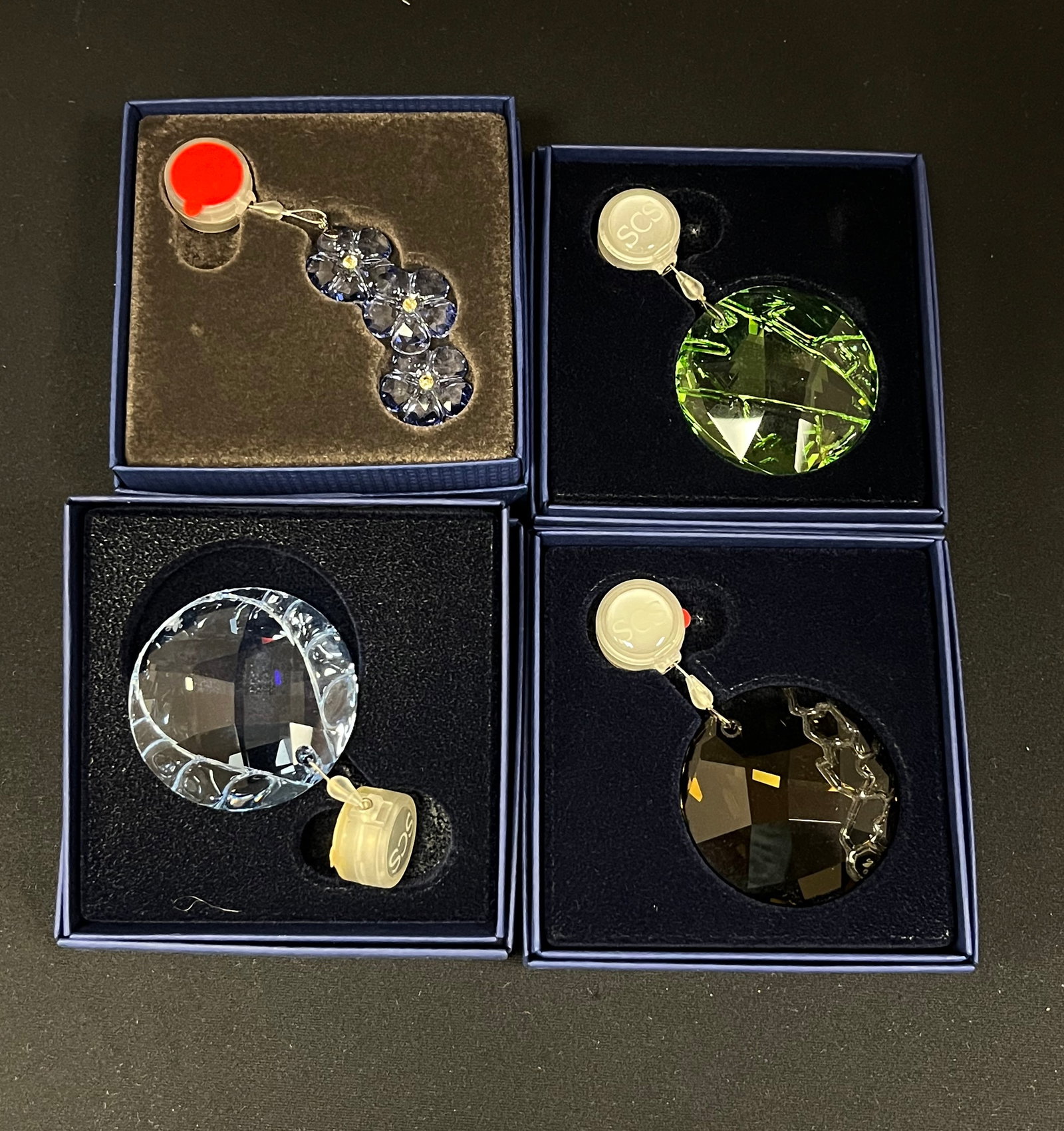 Four Swarovski ornaments: Four Swarovski adjustable ornaments, 2" wide. CONDITION: no chips, cracks, repairs or material defects found. Jaremos attempts to call any material flaw that affects the price, but minor scratches and
