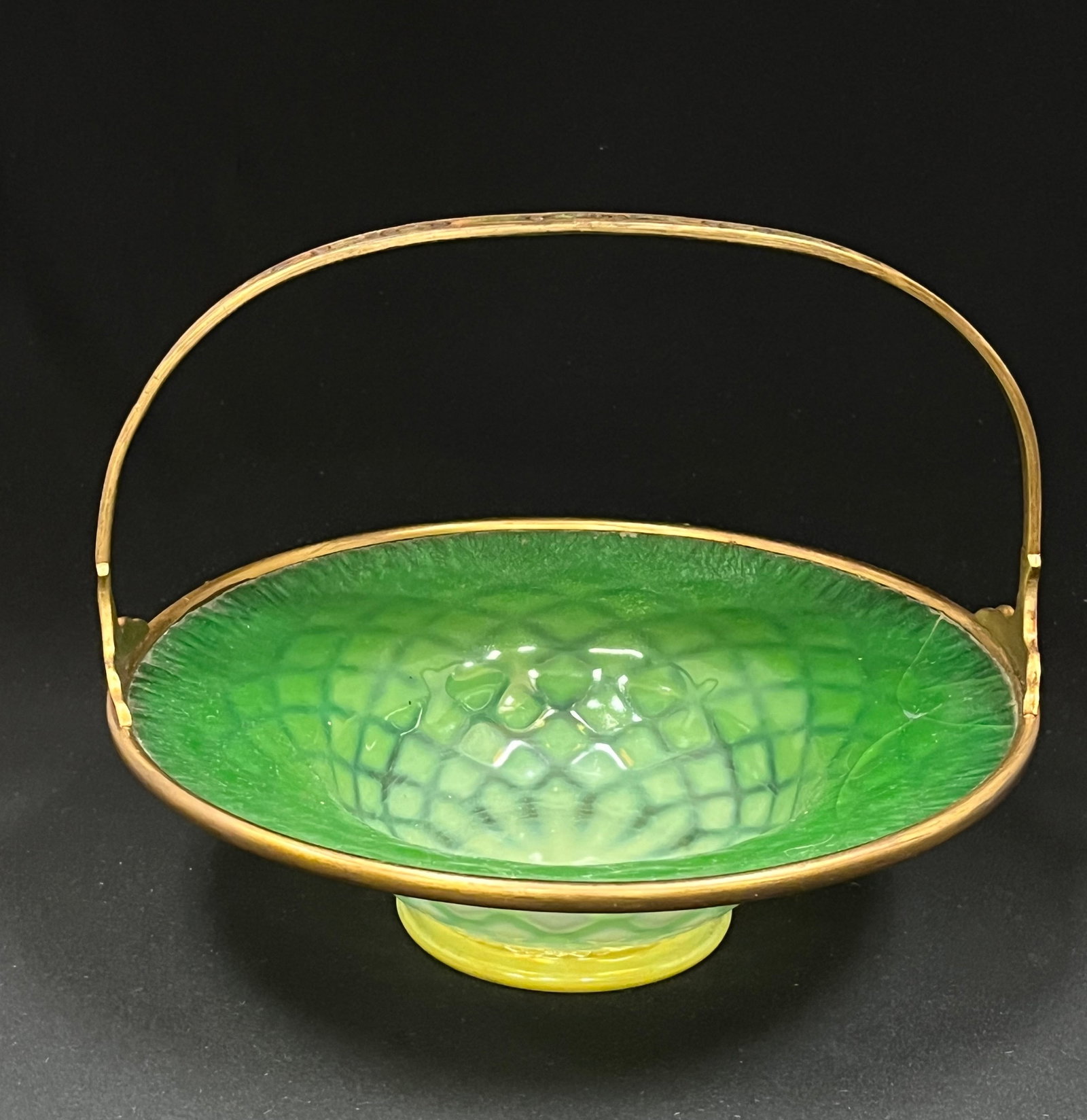 Tiffany glass and bronze basket: Tiffany green pastel optic diamond bowl fitted with a bronze handled basket frame, bronze signed Louis C. Tiffany furnances. Diameter 9 1/4". CONDITION: bowl cracked