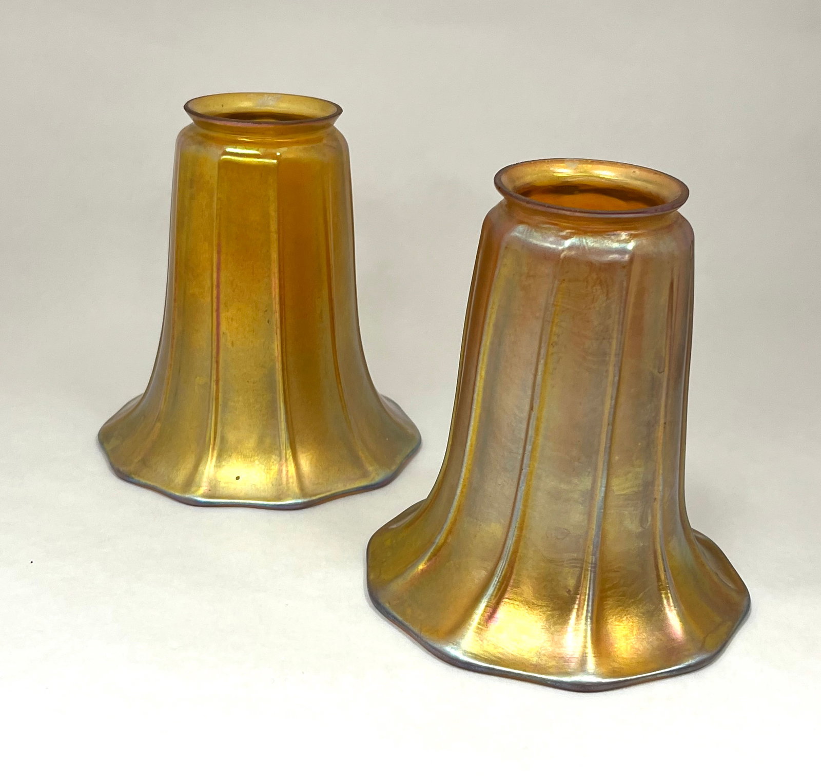Pair of Steuben gold Aurene glass shades: Pair of Steuben ribbed Gold Aurene glass shades each signed with a silver Fleur-de-Lis, 2 1/4" fitter 5 1/4" ht. CONDITION: no chips, cracks, repairs or material defects found. Jaremos attempts to cal