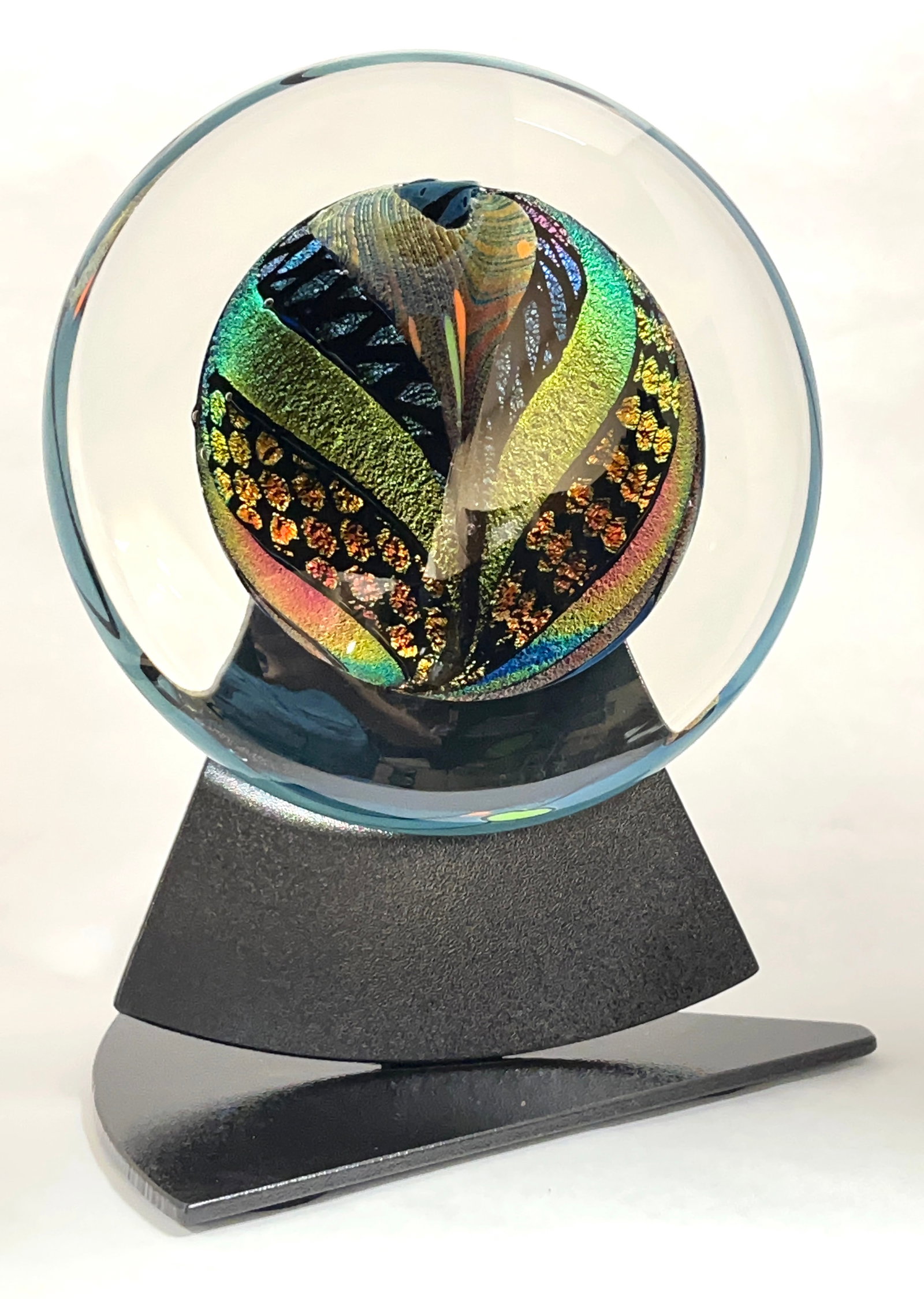 Rolin Karg glass and metal sculpture: Rolin Karg translucent glass disk with a central core of colorful aventurine set on a black metal stand, signed Karg, disk 10" wide overall 16" ht. CONDITION: no chips, cracks, repairs or material def