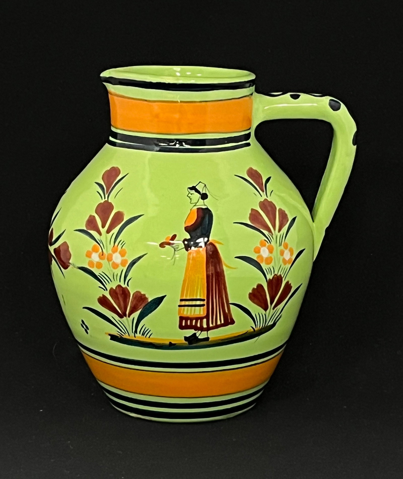 Rare green glaze Quimper pitcher: Rare green glaze Quimper green pitcher with a Bretonne and flowers, marked Henriot Quimper France, 7" ht. CONDITION: no chips, cracks, repairs or material defects found, Jaremos attempts to call any m