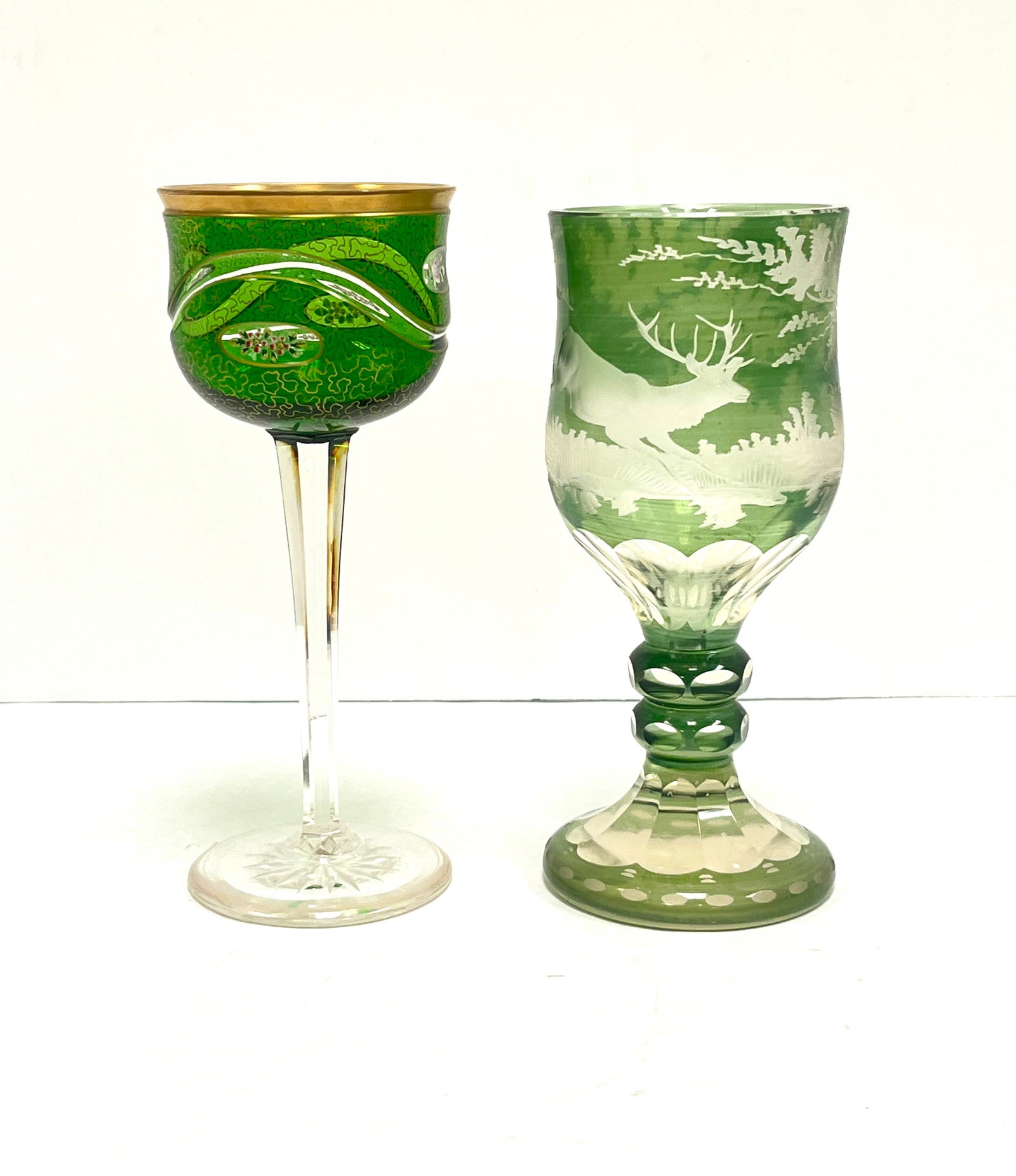2 Bohemian Green Goblets: 2 Bohemian green goblets one with etched deer and forest scene, the other with medallions of roses and etched scrolling; tallest 7 1/2". CONDITION: no chips, cracks, repairs or material defects found,