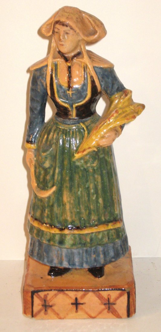Rare Quimper - HR only - Figure of a Bretonne: in "terre cuit vernissee", wearing traditional costume of apron, vest and coif and holding a sickle and a sheaf of wheat. c.1895. Literature: "Quest for Quimper" pg. 205