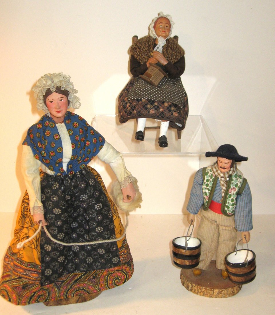 (3) Santons from Provence on wood bases: dressed in country attire including (1) woman seated in a rocking chair; (1) woman holding a spindle of wool and (1) man carrying buckets of milk. Tallest 12"H. 20th C.
