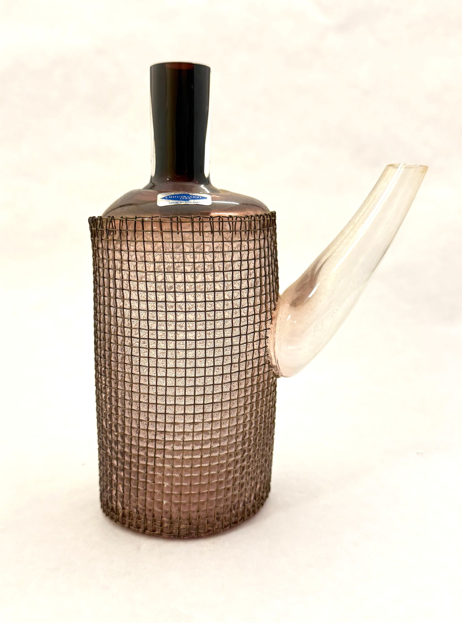 Finnish Art Glass Teapot Vase: Finnish art glass teapot vase in amber glass with clear spout and wire mesh surrounding body, paper label Nuutajarvi 1793 Made in Finland; 7 7/8" ht. CONDITION: no chips, cracks, repairs, or material