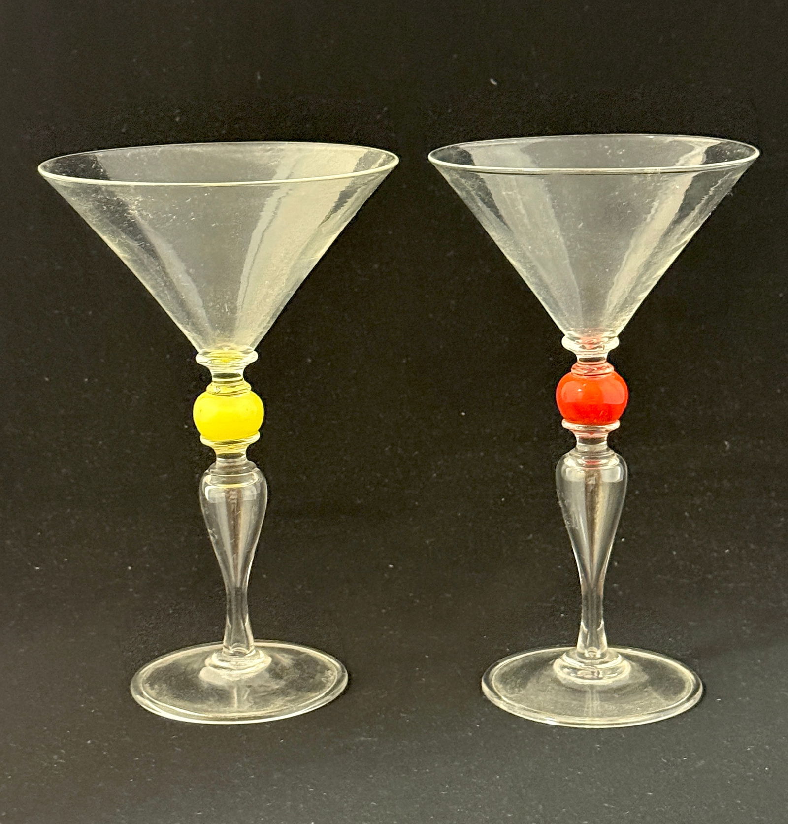 Pair of Dante Marioni Goblets: Pair of Dante Marioni clear glass goblets, one with red standard and one with yellow, signed; 7 3/8" ht. CONDITION: no chips, cracks, repairs, or material defects found, Jaremos attempts to call any m