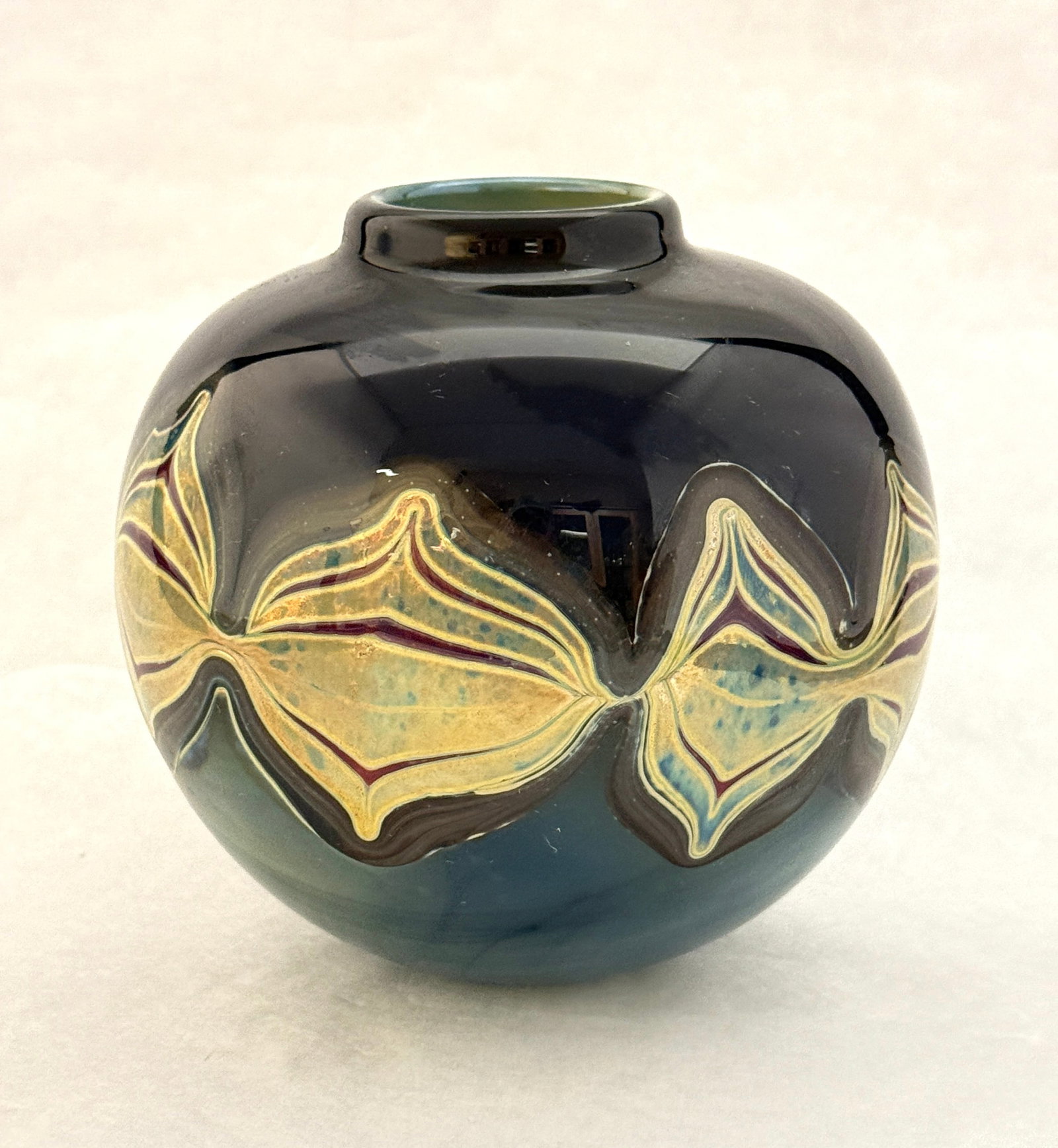 Blue Squat Vase: Blue squat vase with band of gold, green, red, and blue iridescent abstract design. 5" ht. CONDITION: no chips, cracks, repairs, or material defects found, Jaremos attempts to call any material flaw t