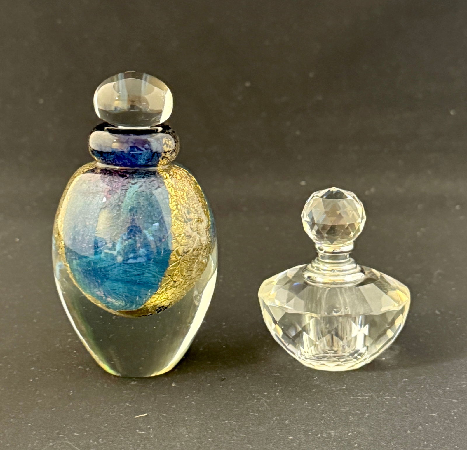 2 Art Glass Perfumes: Oleg Cassini clear with facetted body and stopper with an Eichholt clear with gold and blue interior and clear stopper, both signed; tallest 4" ht. CONDITION: Cassini perfume missing internal stopper