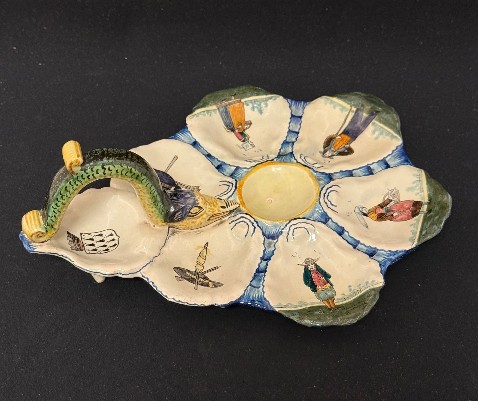 HB Rare Form Oyster Plate: HB French faience RARE form oyster serving plate with serpent handle decorated with 4 Bretons, apparel and musical instruments; length 10". c. 1883-1904 CONDITION: professional restoration to one oyst