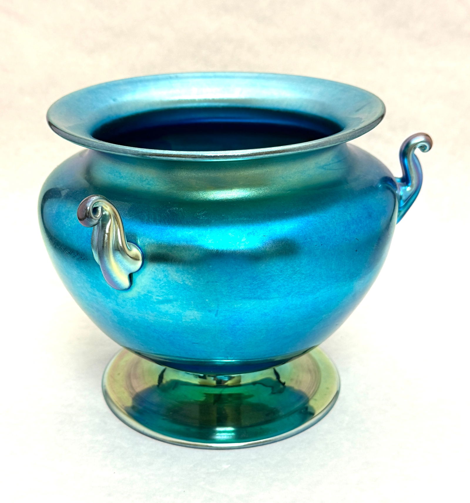 Steuben Blue Iridescent Bowl: Steuben blue iridescent three handle footed bowl, signed Steuben Aurene 6627; ht 6 1/4". CONDITION: no chips, cracks, repairs or material defects found, Jaremos attempts to call any material flaw that