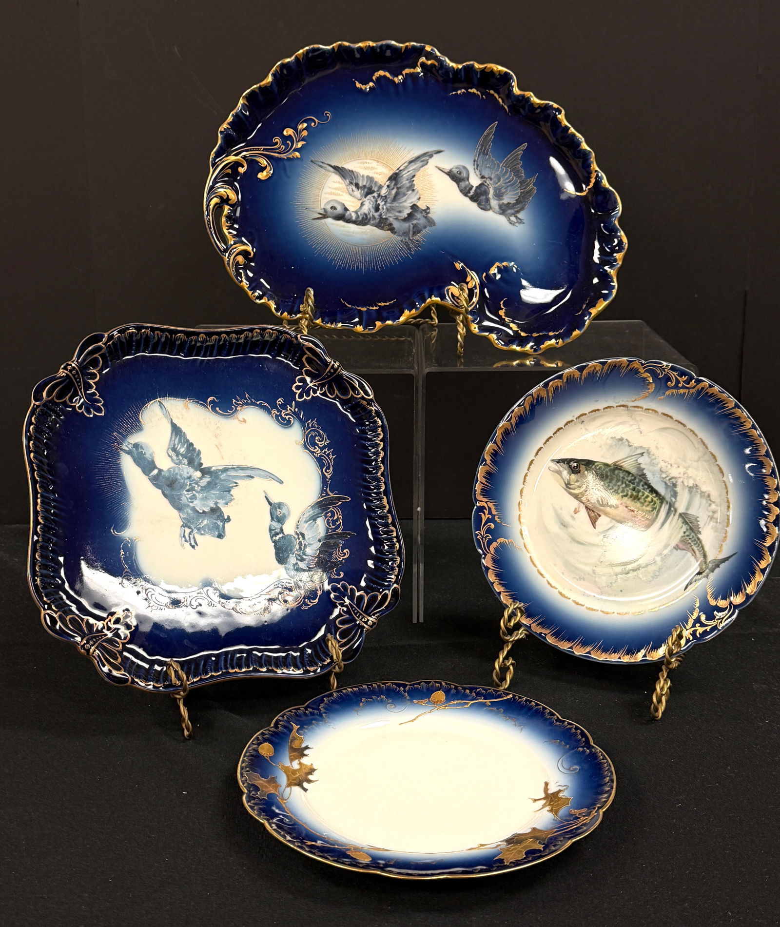 4 Pairpoint Cobalt Porcelain Trays: 4 Pairpoint porcelain cobalt trays including a rectangular tray with flying Geese, a kidney shape tray with Geese, a plane dinner and a fish plate, all signed. Largest 13" long. CONDITION: no chips, c