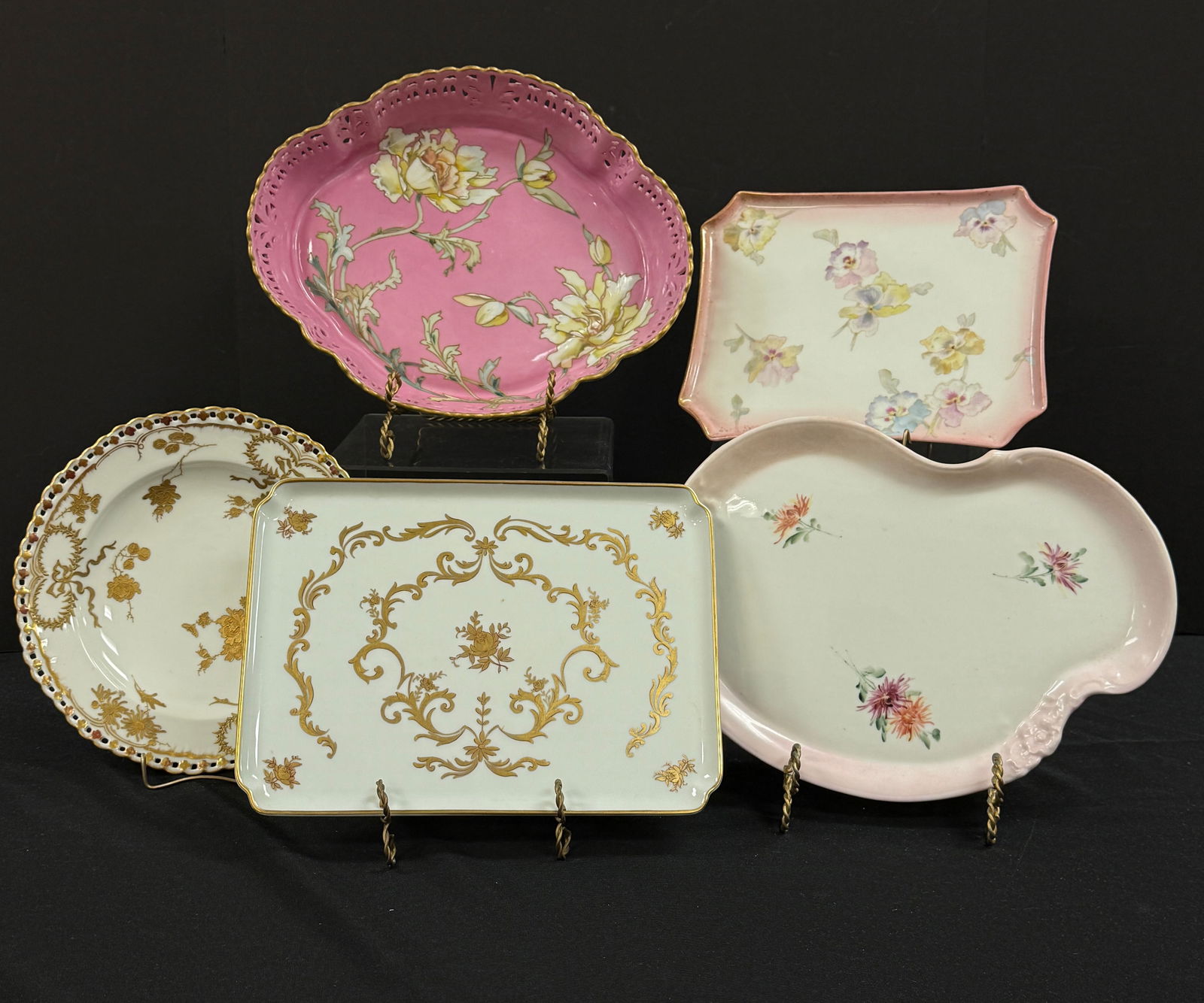 5 Limoges and Pairpoint trays: 5 Porcelain trays including a pink reticulated center tray with flowers, and four others with scrolling a flowers, 4 signed Pairpoint Limoges, one signed Limoges, largest 12" long. CONDITION: no chips