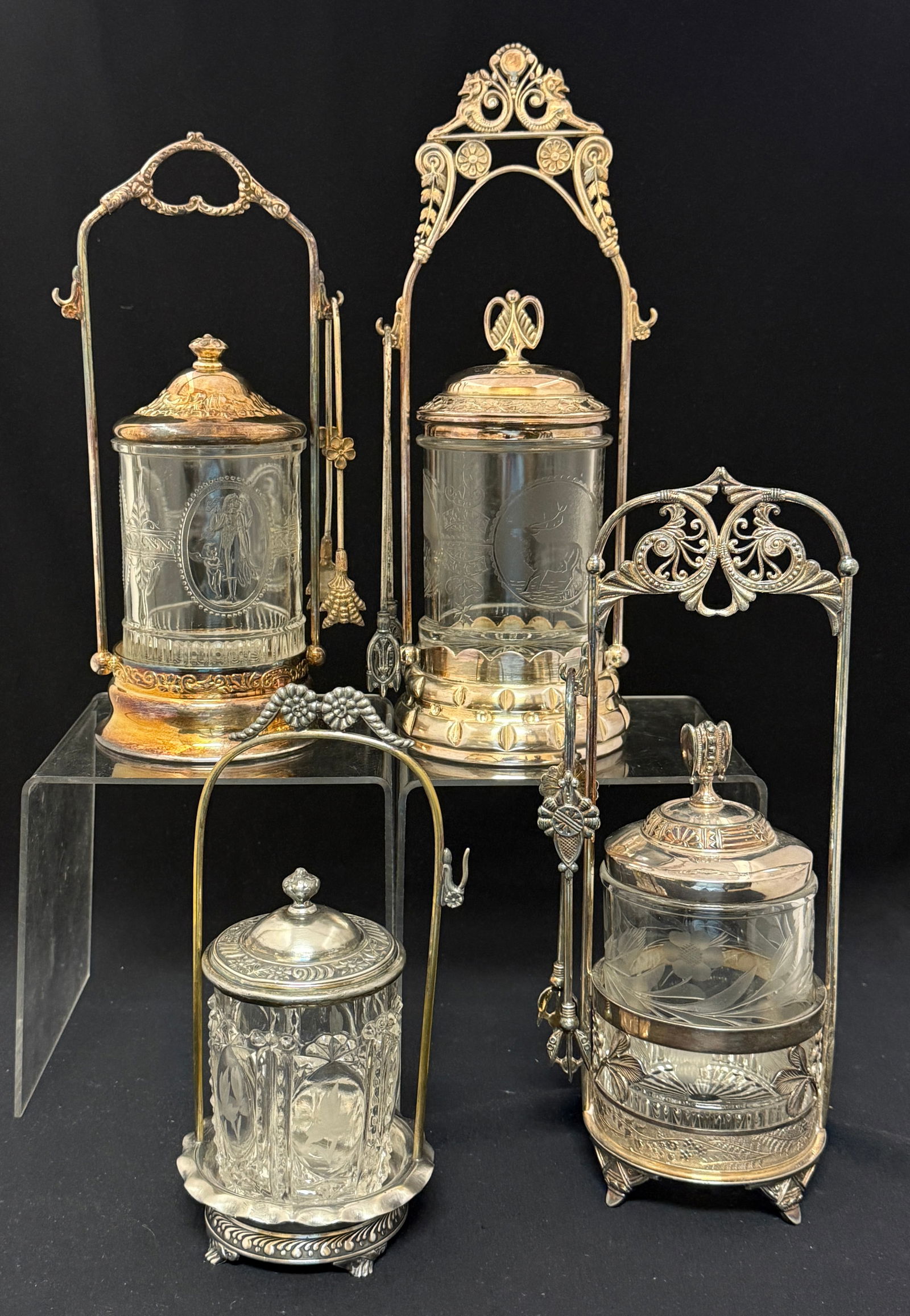 4 Pairpoint Frame Pickle Castors: 4 Pairpoint framed crystal pickle castors including 2 etched with flowers, an EAPG Richards and Hartley Cupid and Venus, and one with etched stags, 3 with forks, all marked Pairpoint; tallest ht 11 3/