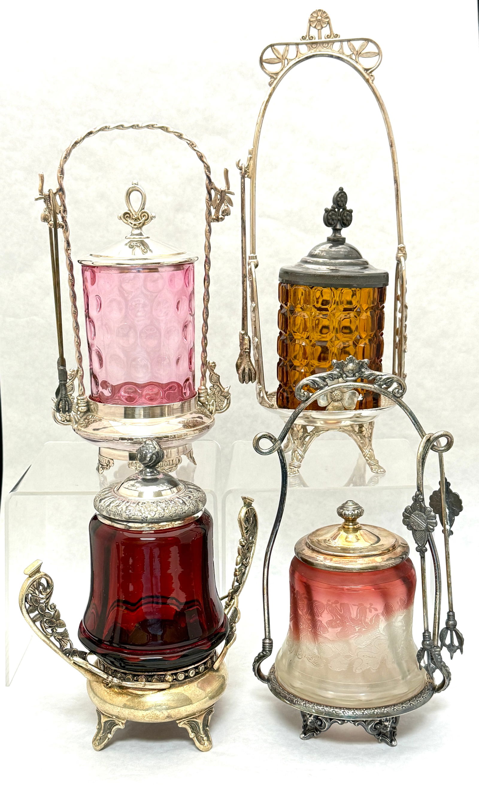 4 Victorian Pickle Castors: 4 Victorian pickle castors including an etched Rubina, a thumbprint cranberry with fork, a dark ruby with 2 handle holder, and an amber block pattern with fork and in a marked Pairpoint holder; talles
