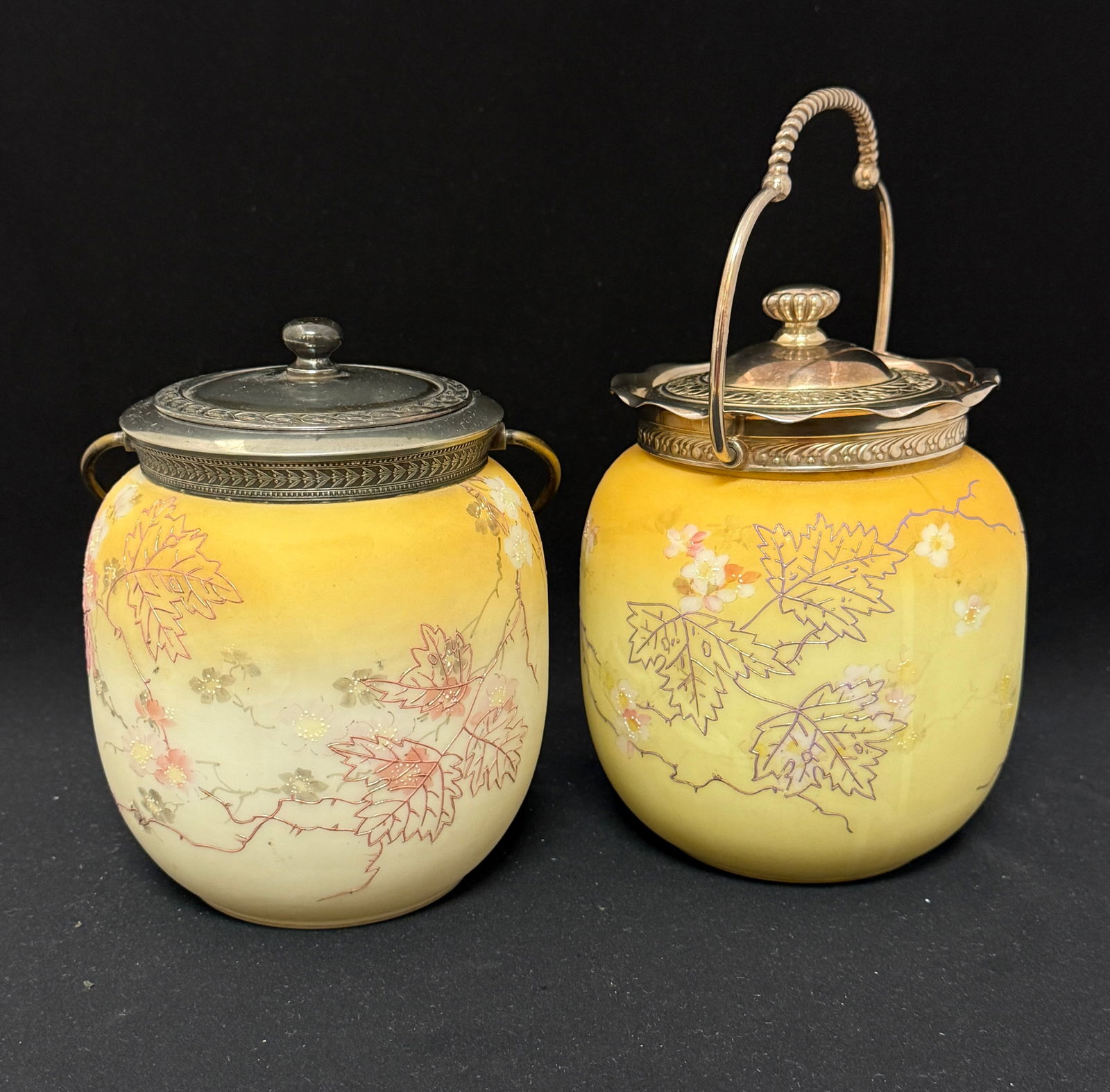 2 Mt. Washington Biscuit Jars: 2 Mt. Washington biscuit jars with enameled oak leaves and flowers, lids marked MW; ht 7 1/2". CONDITION: no chips, cracks, repairs or material defects found, Jaremos attempts to call any material fla