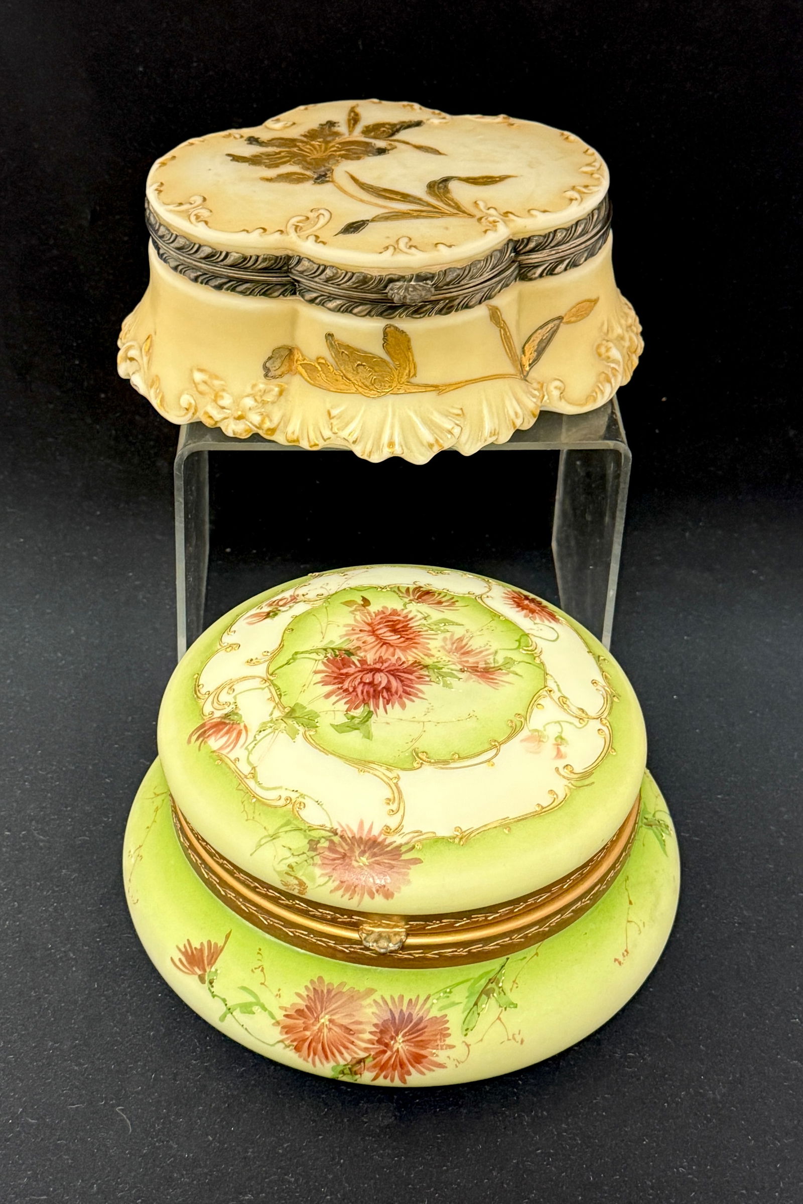 2 Crown Milano Dresser Jars: 2 Crown Milano dresser jars one round in green with a white band and rose spider mums no lining and an oval scalloped cream colored with gold embossed flower with felt interior lid and bottom; largest