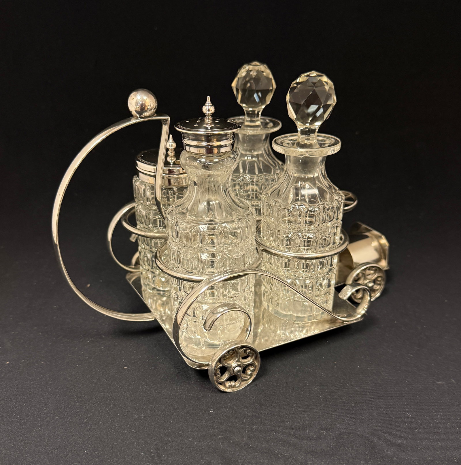 Cut Glass Cruet Set: Four piece block cut cruet set consisting of two bottles, a shaker and mustard set in an English caddy in the form of a car, 6 1/2" ht. CONDITION: no chips, cracks, repairs, or material defects found,