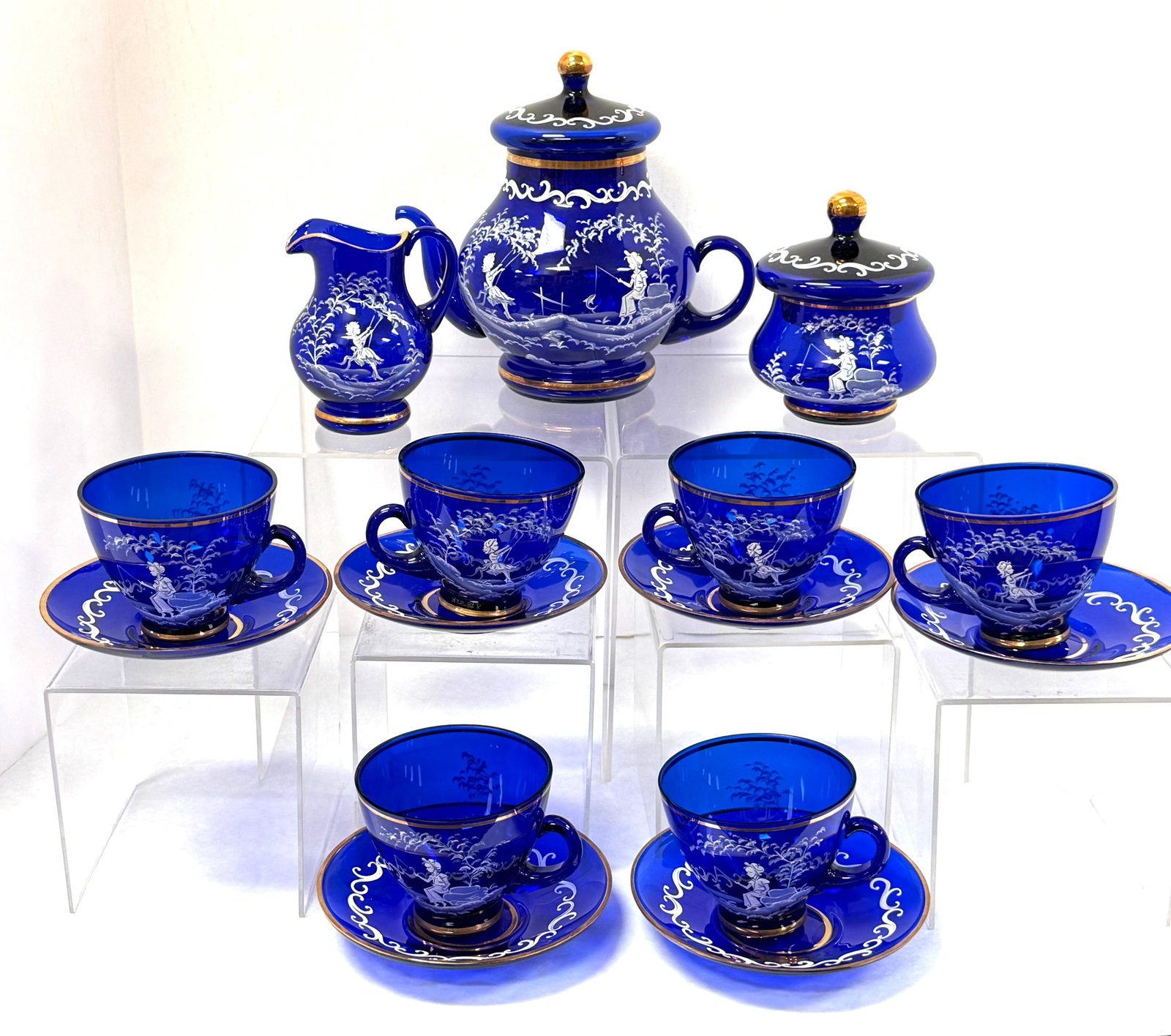 Mary Gregory Cobalt Tea Set: Mary Gregory cobalt blue tea set including teapot, creamer, sugar, and 6 cups and saucers; teapot ht. 8". CONDITION: no chips, cracks, repairs, or material defects found, Jaremos attempts to call any 
