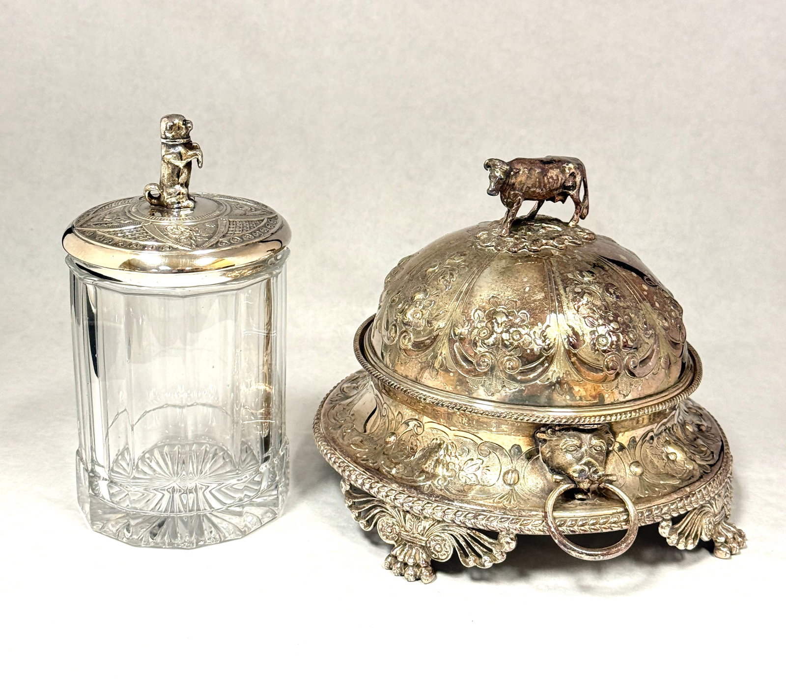 2 Silver Plate Items: 2 silver plate serving pieces, one covered butter with cow finial and a small covered jar with dog finial; tallest ht. 6 7/8". CONDITION: no chips, cracks, repairs, or material defects found, Jaremos