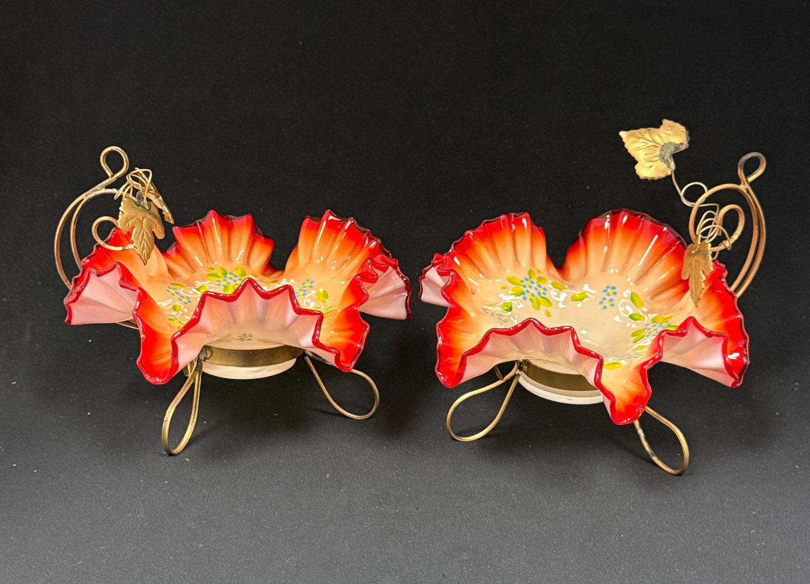 Two Peach Glass and Metal baskets: Two peach bowls with cherry red ruffled rims and enameled flowers set in a wire leaf embossed caddy, 6" ht. CONDITION: no chips, cracks, repairs, or material defects found, Jaremos attempts to call