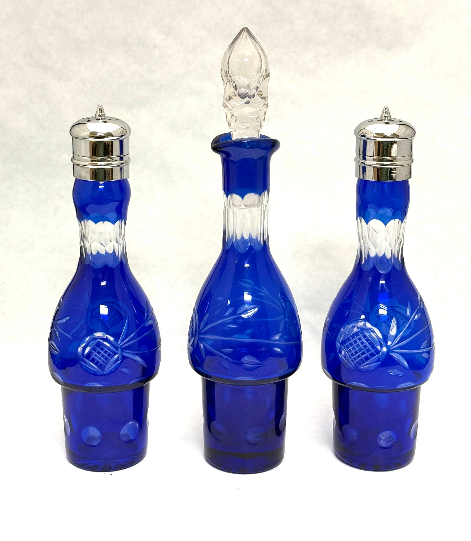 3 Cut to Clear Cobalt Bottles: 3 cobalt cut to clear condiment bottles, 2 shakers, 1 oil/vinegar; tallest 8 7/8". CONDITION: no chips, cracks, repairs, or material defects found, Jaremos attempts to call any material flaw that