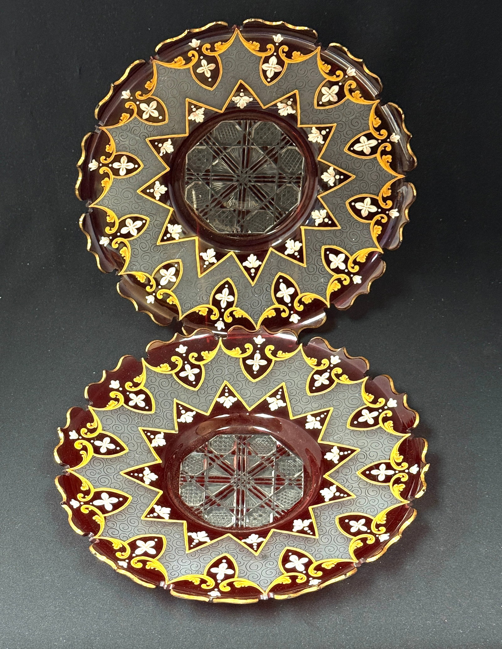 2 Bohemian Plates: 2 Bohemian cranberry cut to clear plates with scalloped rims and enameled white flowers and gold accents, has etching and a cut glass bottom; diameter 9 7/8". CONDITION: one plate has rim chip, see
