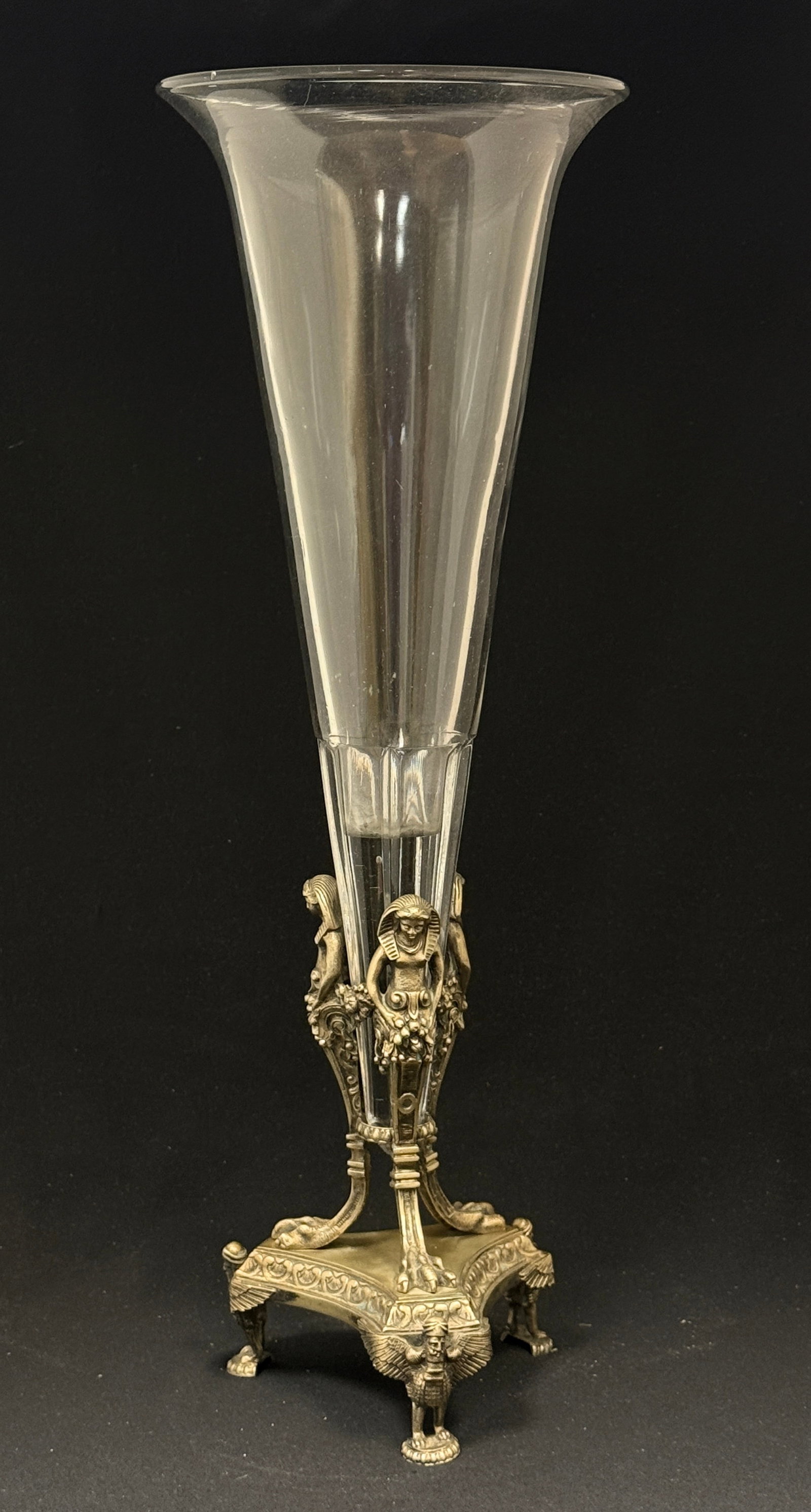 Glass and Metal Trumpet Epergne: Tall clear glass single trumpet shaped epergne set in metal holder with Egyptian women; ht. 17 7/8". CONDITION: no chips, cracks, repairs, or material defects found, Jaremos attempts to call any mater