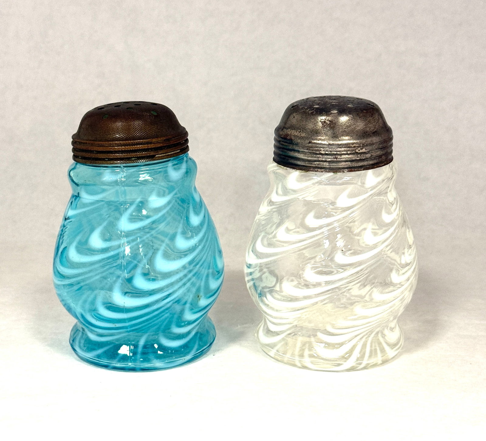 2 Opalescent Blown Twist Shakers: 2 opalescent blown twist sugar shakers in white and blue; ht. 4 3/4". CONDITION: no chips, cracks, repairs, or material defects found, Jaremos attempts to call any material flaw that affects the price