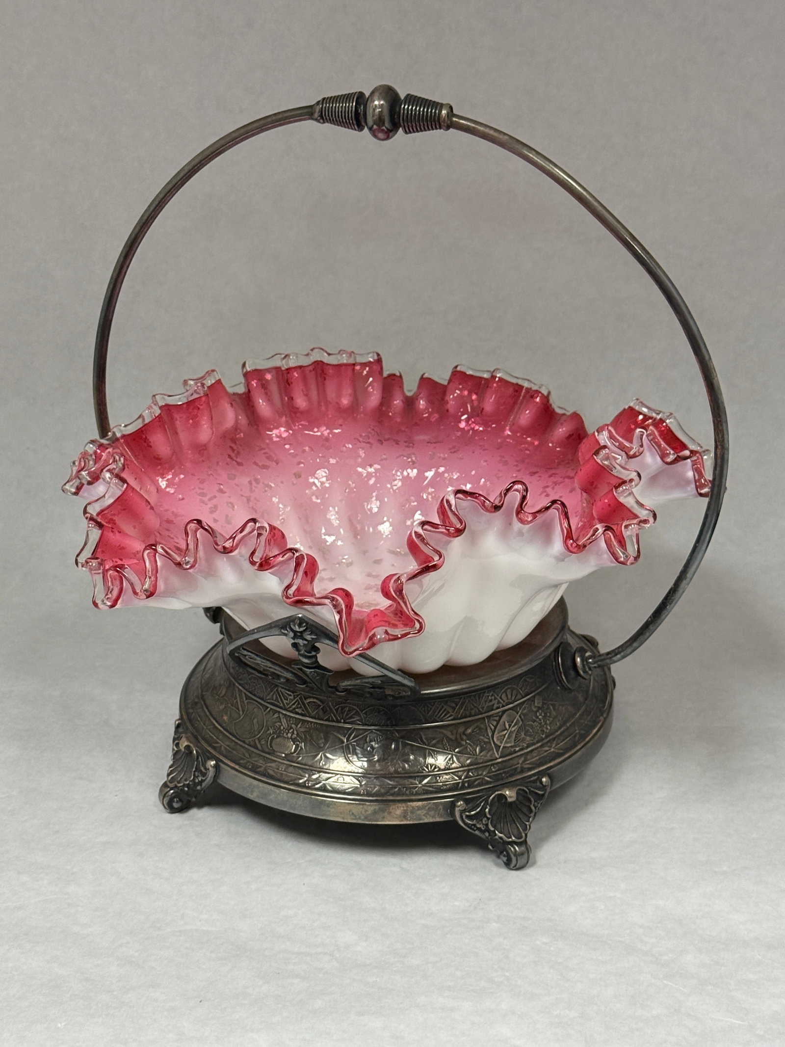 Opalescent Bride's Basket in Frame: Opalescent cranberry with mica bride's basket in metal frame; diameter 10". CONDITION: no chips, cracks, repairs, or material defects found, Jaremos attempts to call any material flaw that affects