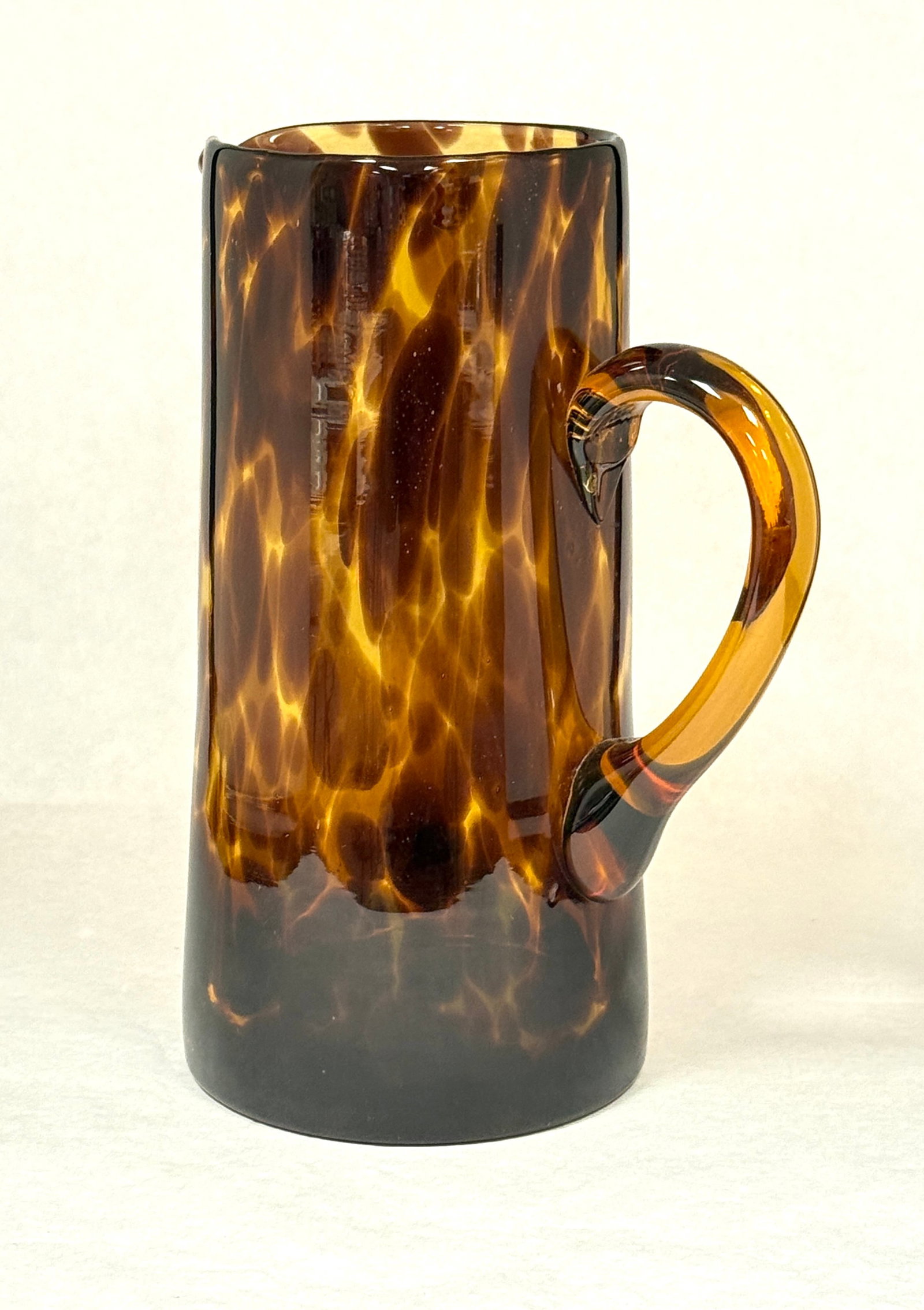 Tankard in Tortoise Shell Color: Glass Tortoise shell colored tankard; ht. 8 1/2". CONDITION: no chips, cracks, repairs, or material defects found, Jaremos attempts to call any material flaw that affects the price, but minor