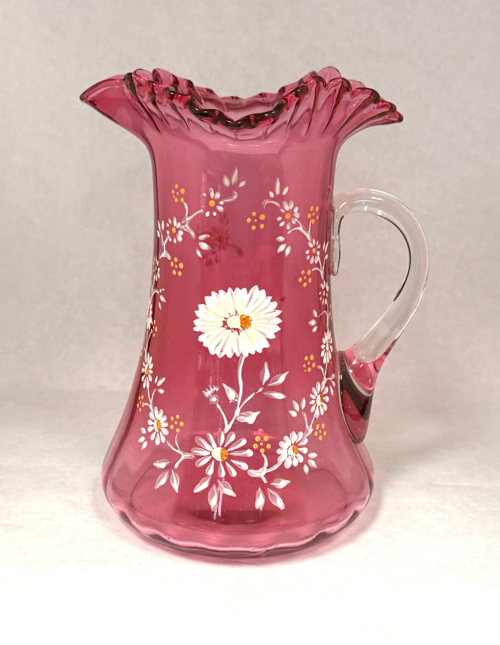 Cranberry Enameled Pitcher: Cranberry pitcher with enameled daisies and crimp ruffle rim; ht. 9 1/2". CONDITION: no chips, cracks, repairs, or material defects found, Jaremos attempts to call any material flaw that affects the