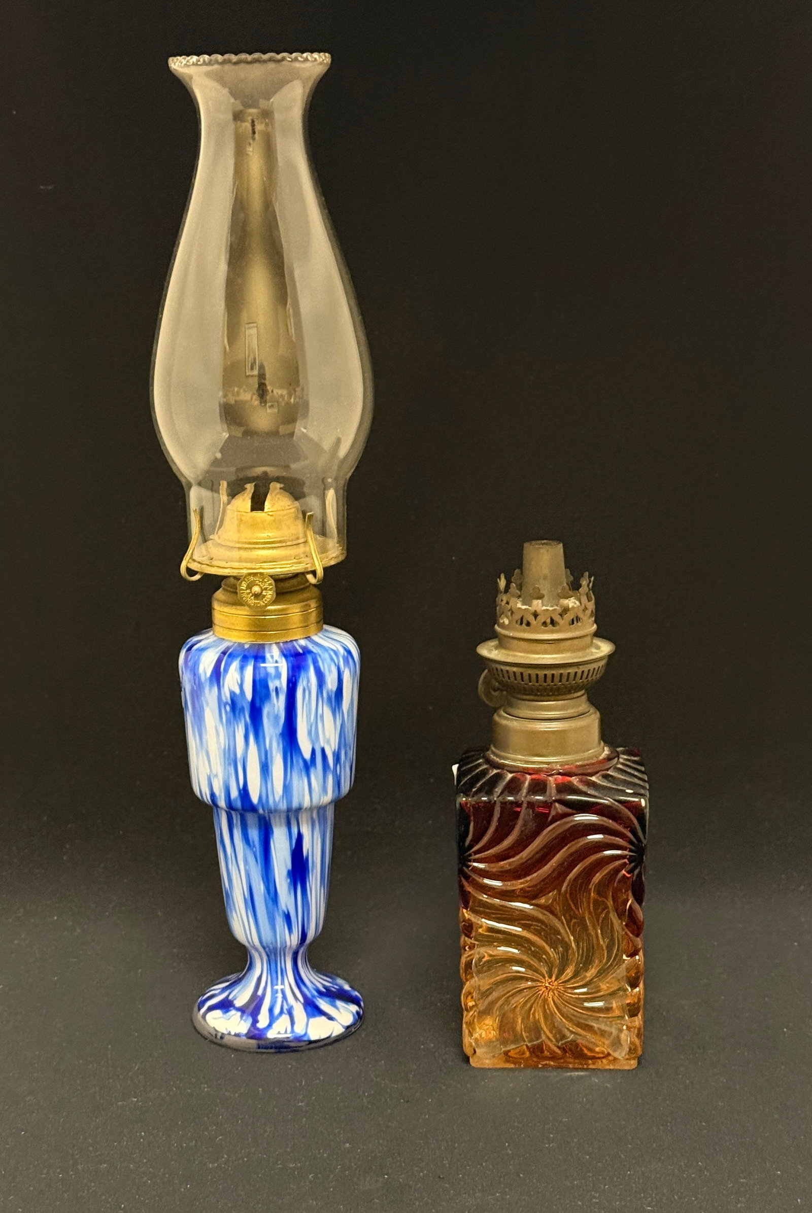2 Oil Lamps: 2 oil lamps including a Baccarat and a blue mottled satin glass; tallest with shade 15". CONDITION: no chips, cracks, repairs, or material defects found, Jaremos attempts to call any material flaw tha