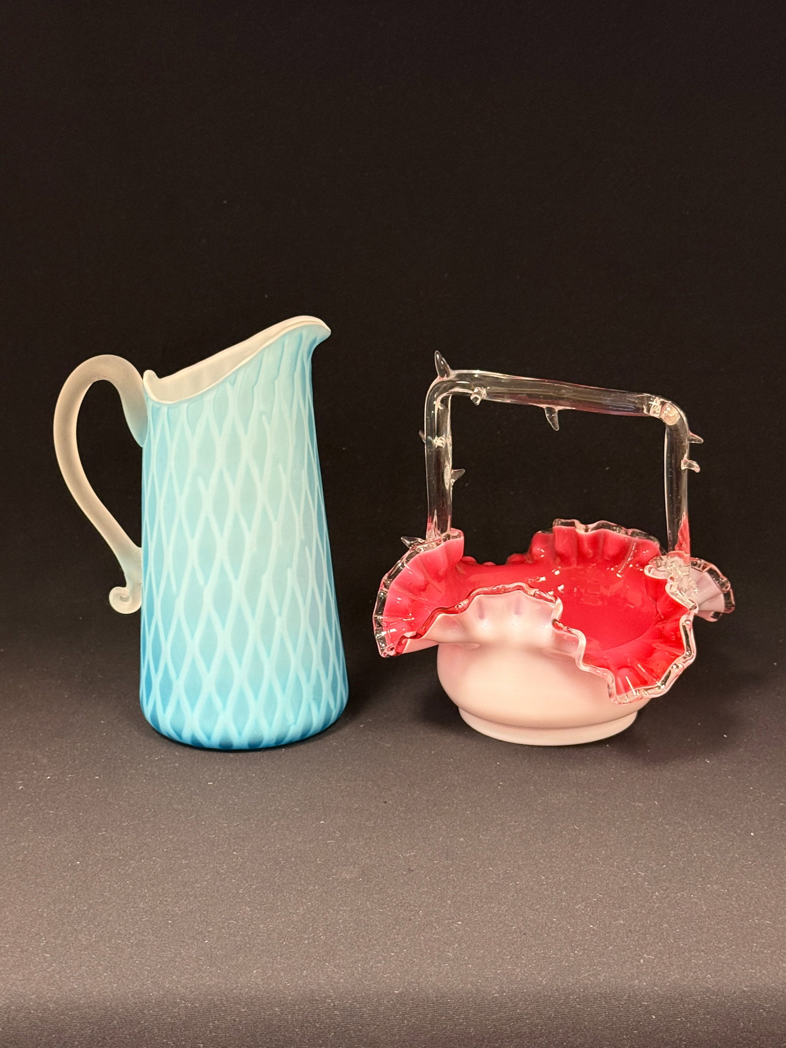 2 Victorian Items: 2 Victorian items including an MOP blue diamond quilt air trapped pitcher and a pink and opal satin glass basket with a clear applied handle and thorns; tallest 7 1/2". CONDITION: no chips, cracks,