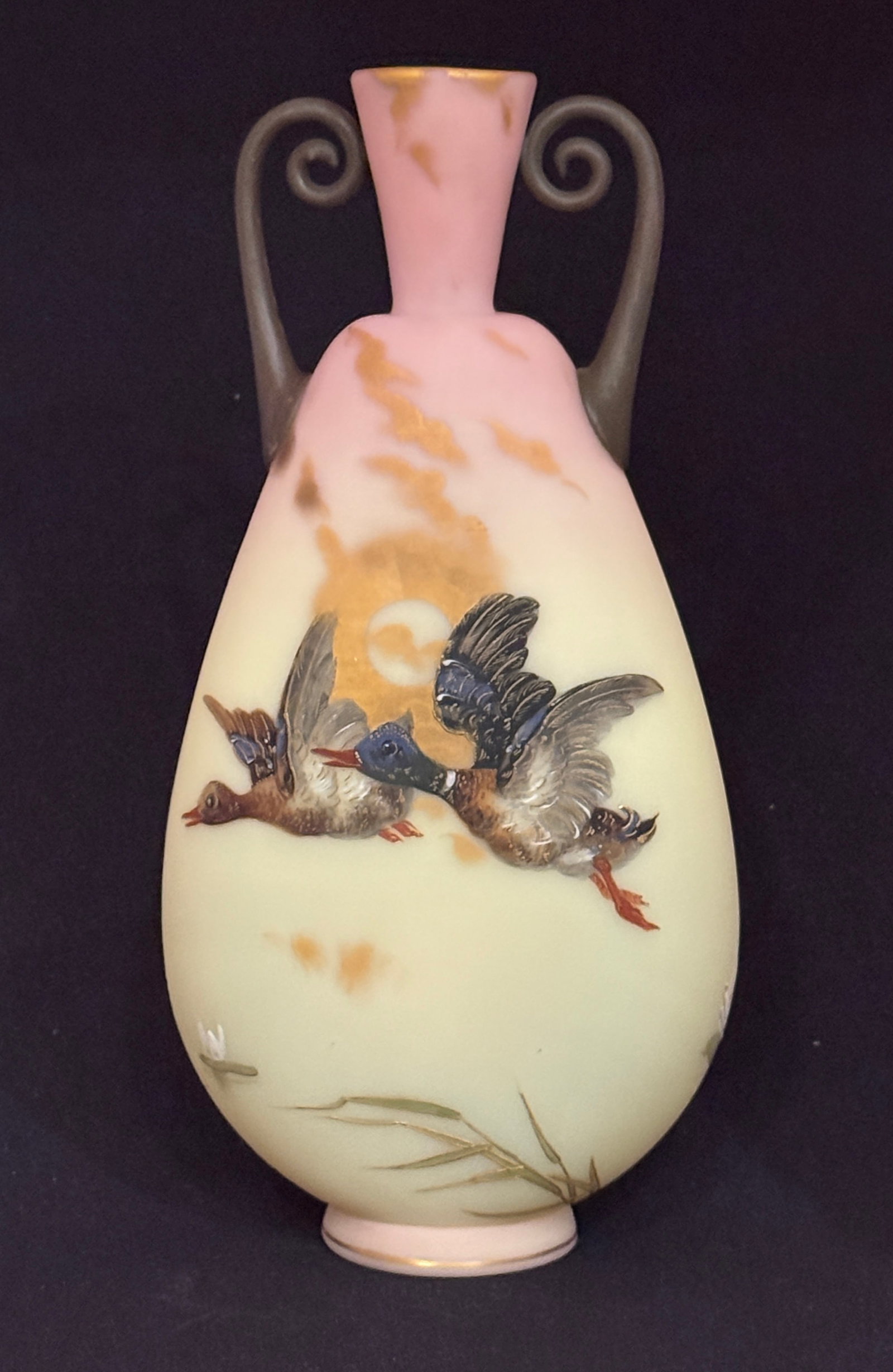 Mt. Washington Burmese Vase: Mt Washington flat sided Burmese two handled vase decorated with Guba Ducks flying in front of a gold sun and clouds, reverse with pussy willows, 11" ht. CONDITION: no chips, cracks, repairs, or