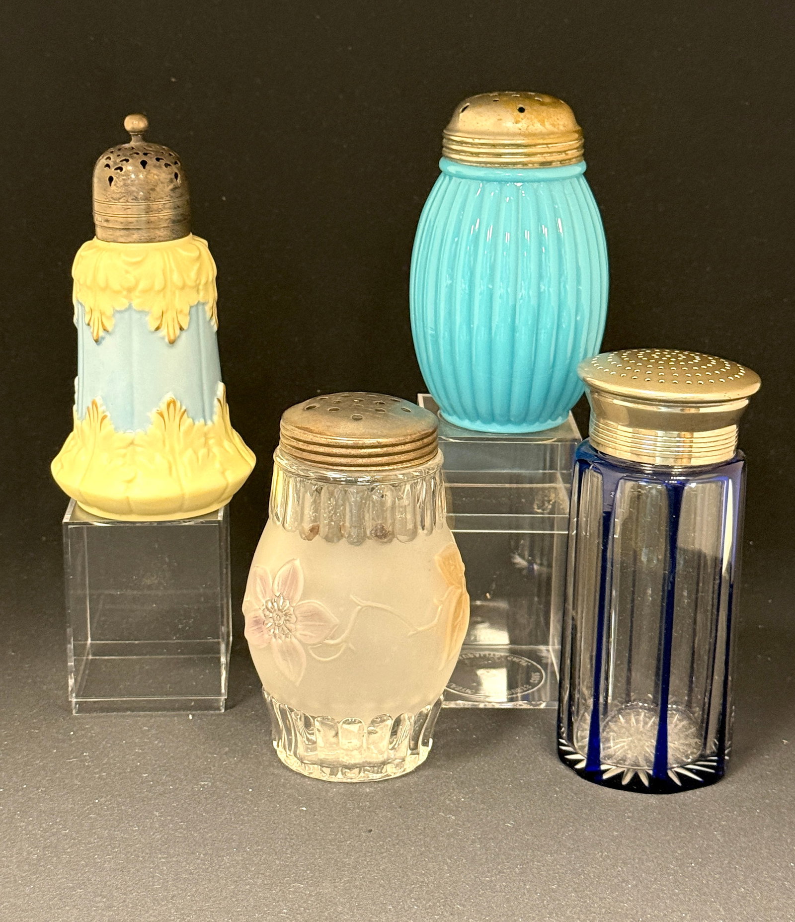 4 Various Victorian Shakers: 4 Victorian shakers including an English Locke powder shaker with scrolling yellow/blue, an 1892 flower and pleat frosted shaker, a blue cut to clear, and a many lobed blue; tallest 6". CONDITION: no