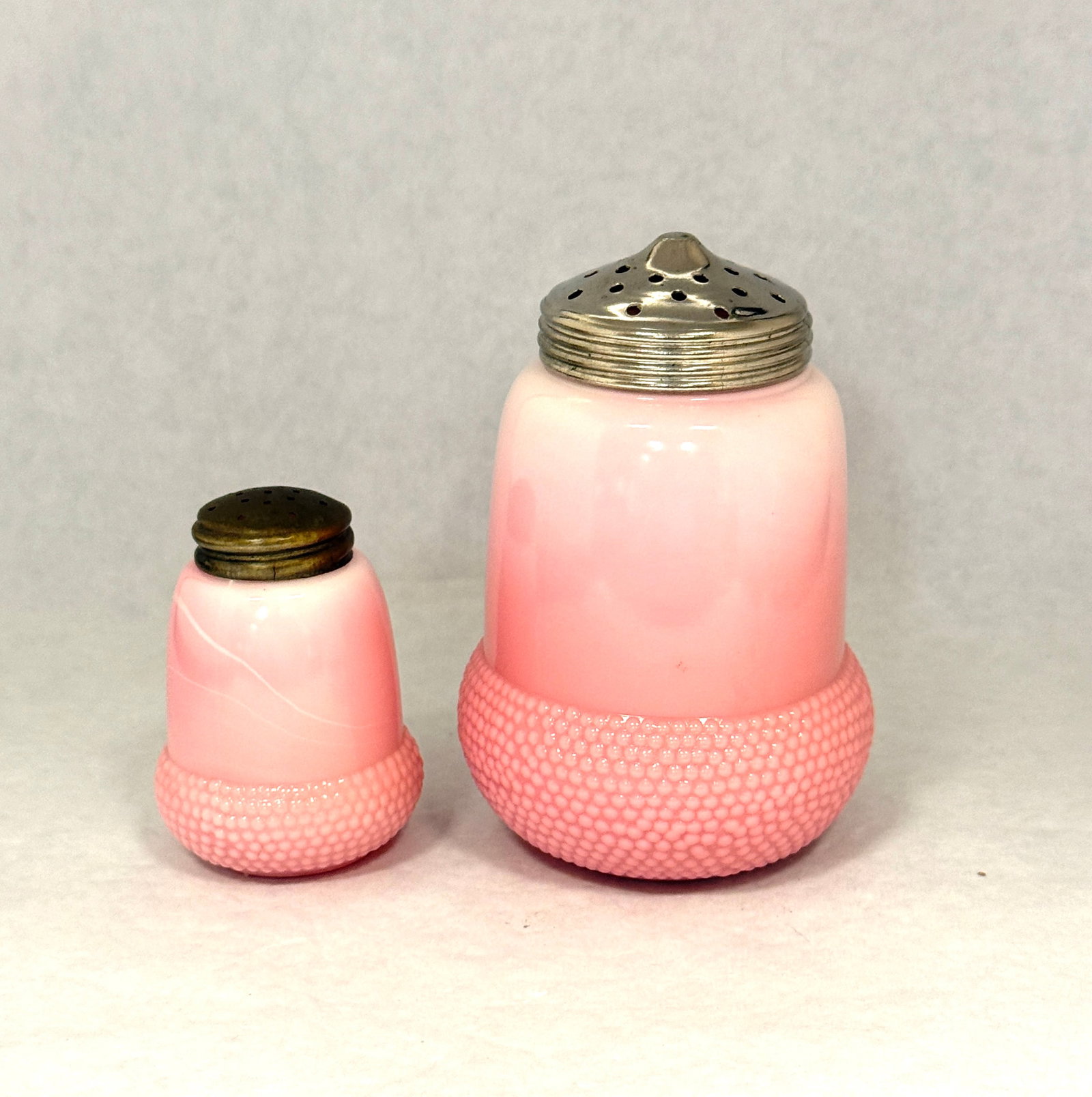 2 Acorn Pattern Shakers: 2 Pink Opaque Beaumont Glass shakers in the acorn pattern, including a sugar and salt, tallest 5" ht. CONDITION: no chips, cracks, repairs, or material defects found, Jaremos attempts to call any mate