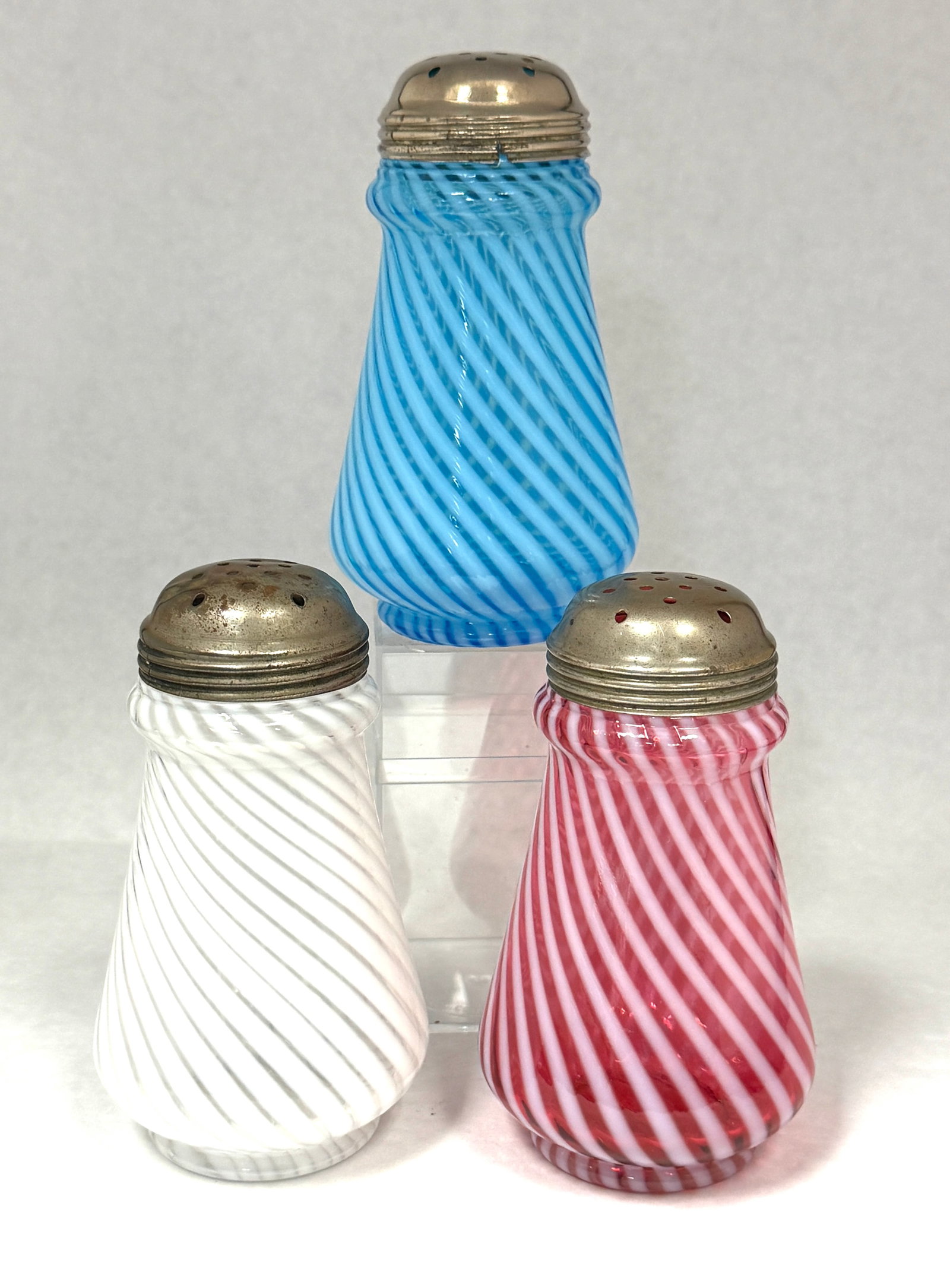 3 Opalescent Sugar Shakers: 3 opalescent ring neck swirl sugar shakers in white, blue, and cranberry; ht. 5 1/4". CONDITION: no chips, cracks, repairs, or material defects found, Jaremos attempts to call any material flaw that a