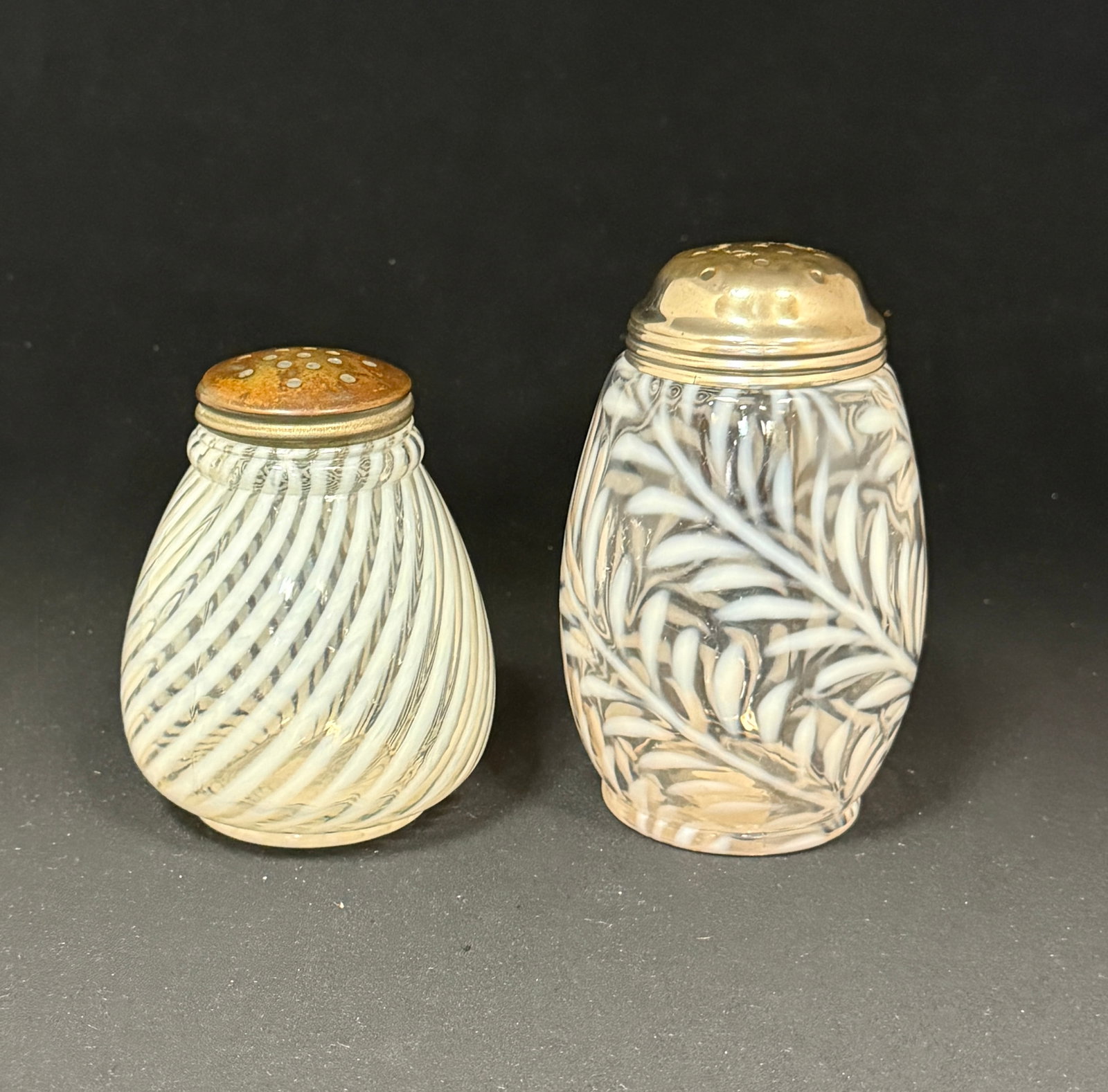 2 Opalescent Sugar Shakers: 2 opalescent sugar shakers one clear and white fern and one clear and white swirl; tallest 5". CONDITION: no chips, cracks, repairs, or material defects found, Jaremos attempts to call any material