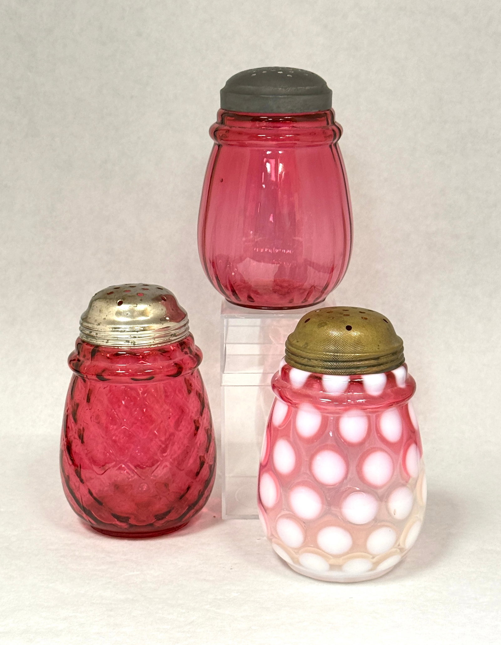 3 Ring Neck Sugar Shakers: 3 ring neck cranberry sugar shakers, one coin spot, one optic diamond, and one optic ribbed; ht. 5". CONDITION: no chips, cracks, repairs, or material defects found, Jaremos attempts to call any