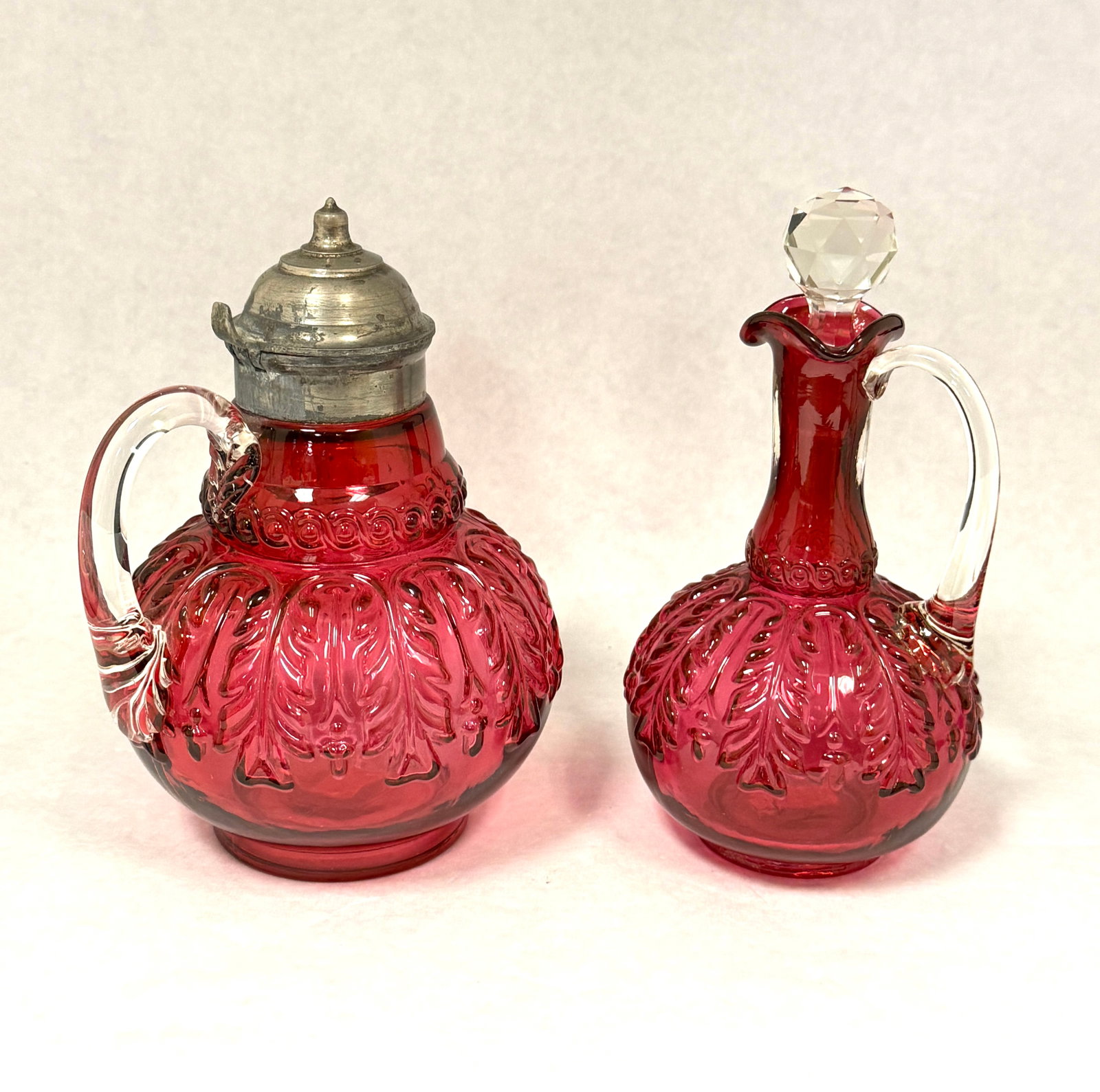 2 Cranberry Leaf Umbrella Items: 2 cranberry leaf umbrella items: cruet and syrup; ht. cruet 7". CONDITION: no chips, cracks, repairs, or material defects found, Jaremos attempts to call any material flaw that affects the price, but