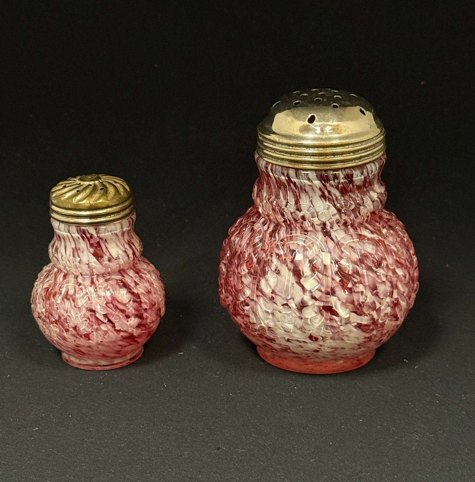 2 Opalescent Splatter Items: 2 Opalescent leaf mold cranberry splatter items: salt shaker and sugar shaker; ht. 4 1/4". CONDITION: no chips, cracks, repairs, or material defects found, Jaremos attempts to call any material flaw t