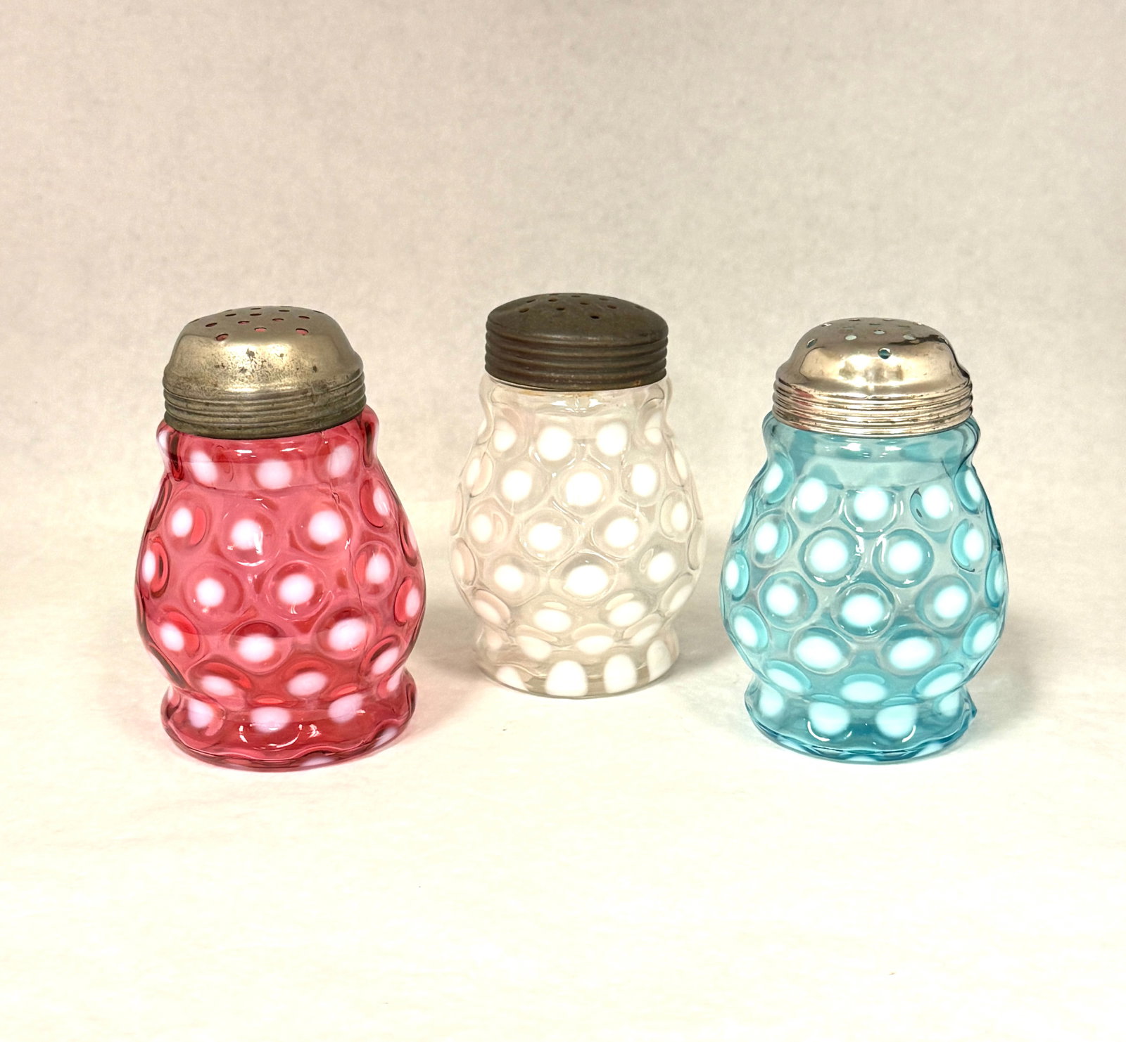 3 Opalescent Coin Sugar Shakers: 3 opalescent wide waist coin spot sugar shakers: cranberry, blue, and white; ht. 4 3/4". CONDITION: no chips, cracks, repairs, or material defects found, Jaremos attempts to call any material flaw