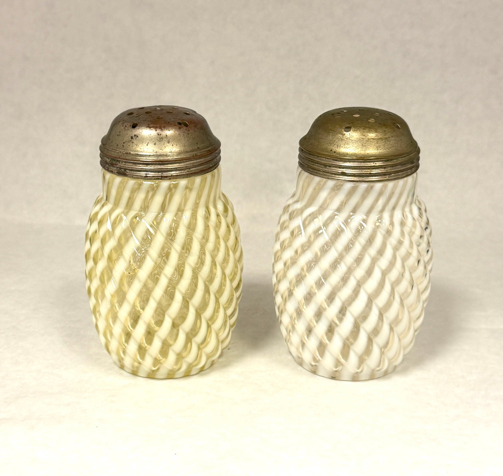 2 Opalescent Shakers: 2 opalescent reverse swirl shakers: one white and a Vaseline; ht. 4 5/8". CONDITION: no chips, cracks, repairs, or material defects found, Jaremos attempts to call any material flaw that affects the p