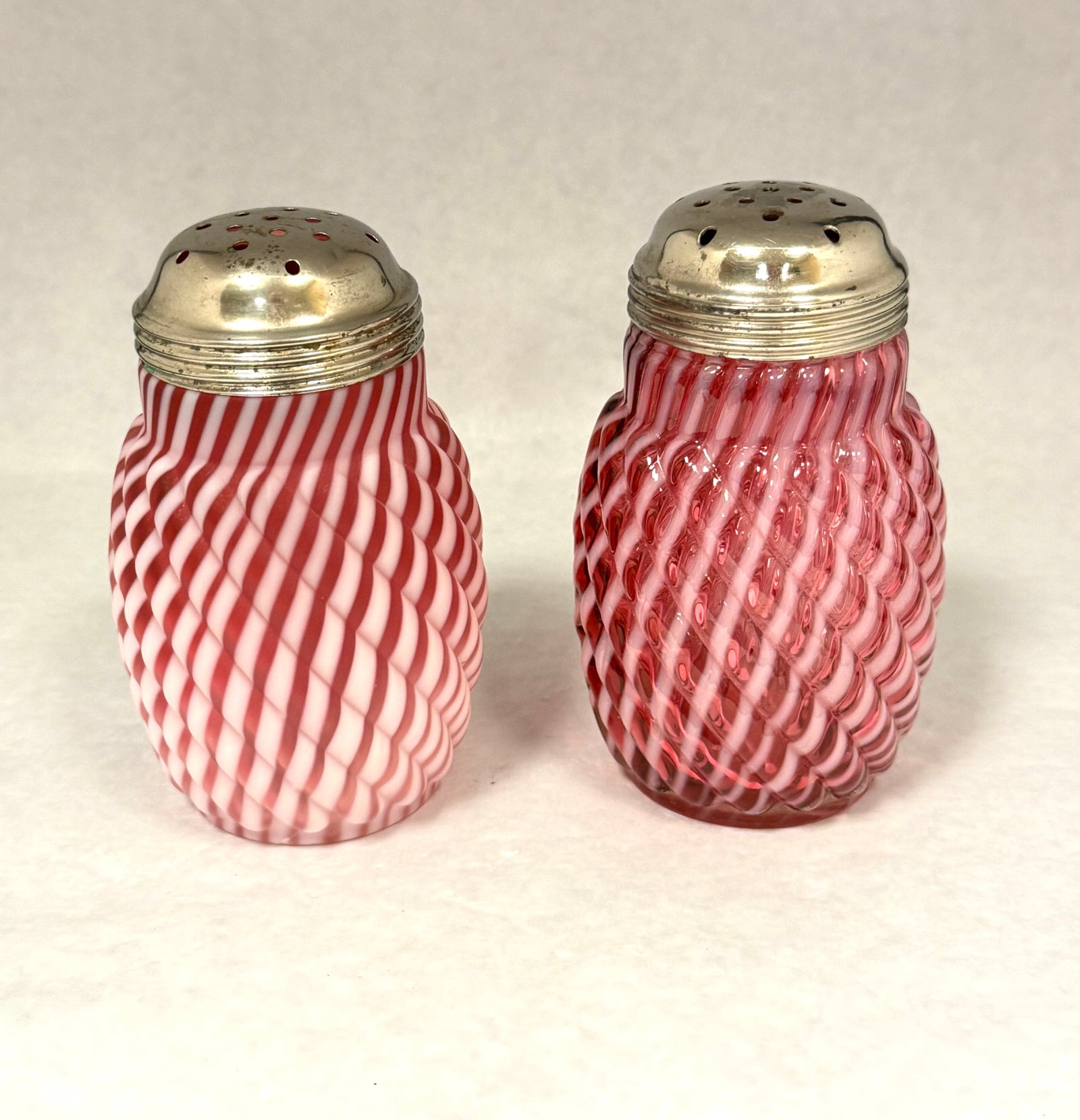 2 Opalescent Shakers: 2 opalescent reverse swirl shakers: one cranberry, one cranberry satin; ht. 4 3/4". CONDITION: no chips, cracks, repairs, or material defects found, Jaremos attempts to call any material flaw that aff