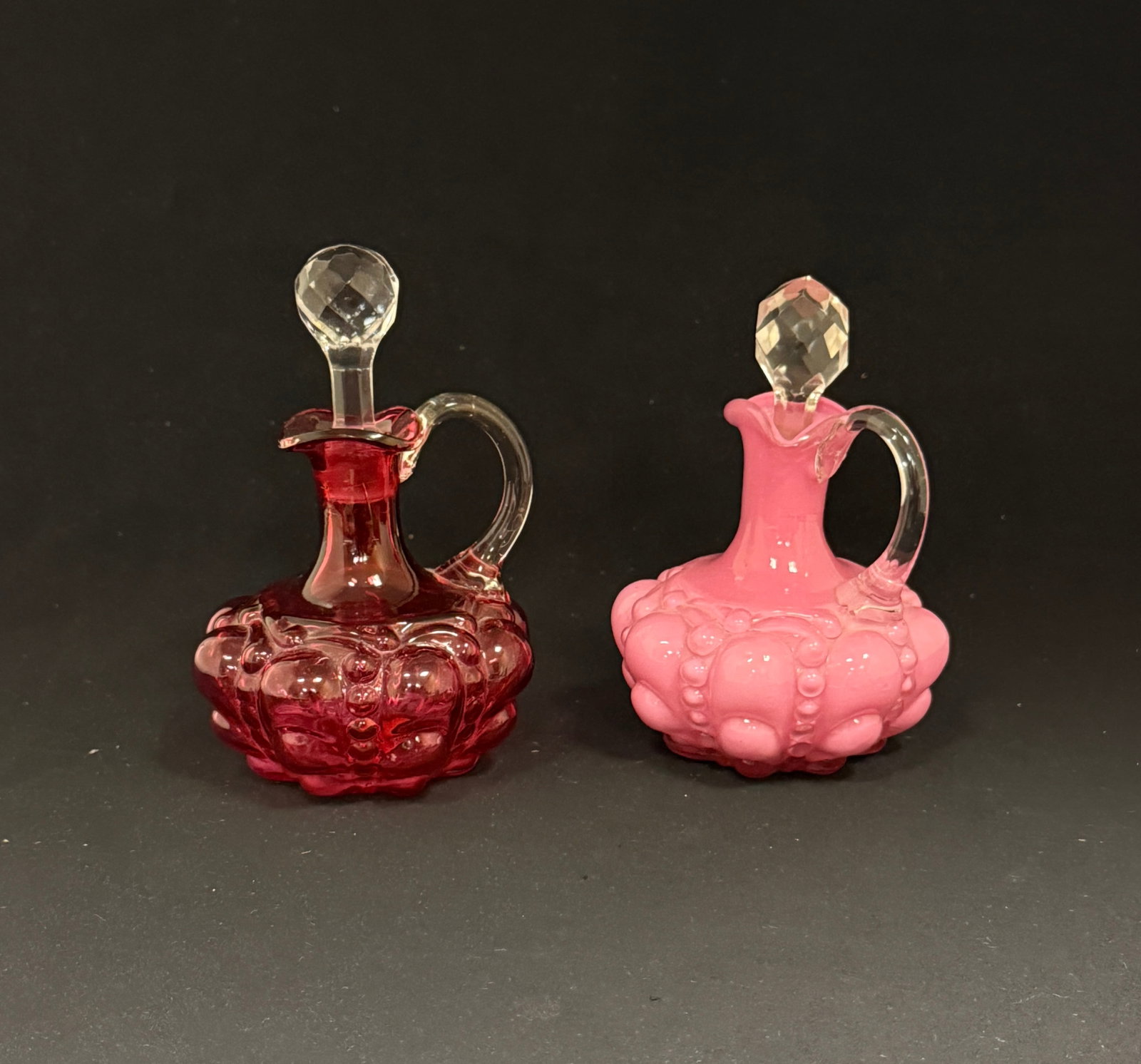 2 Guttate Cruets: 2 Guttate cruets one pink and one cranberry; ht. 5 1/2". CONDITION: no chips, cracks, repairs, or material defects found, Jaremos attempts to call any material flaw that affects the price, but minor s