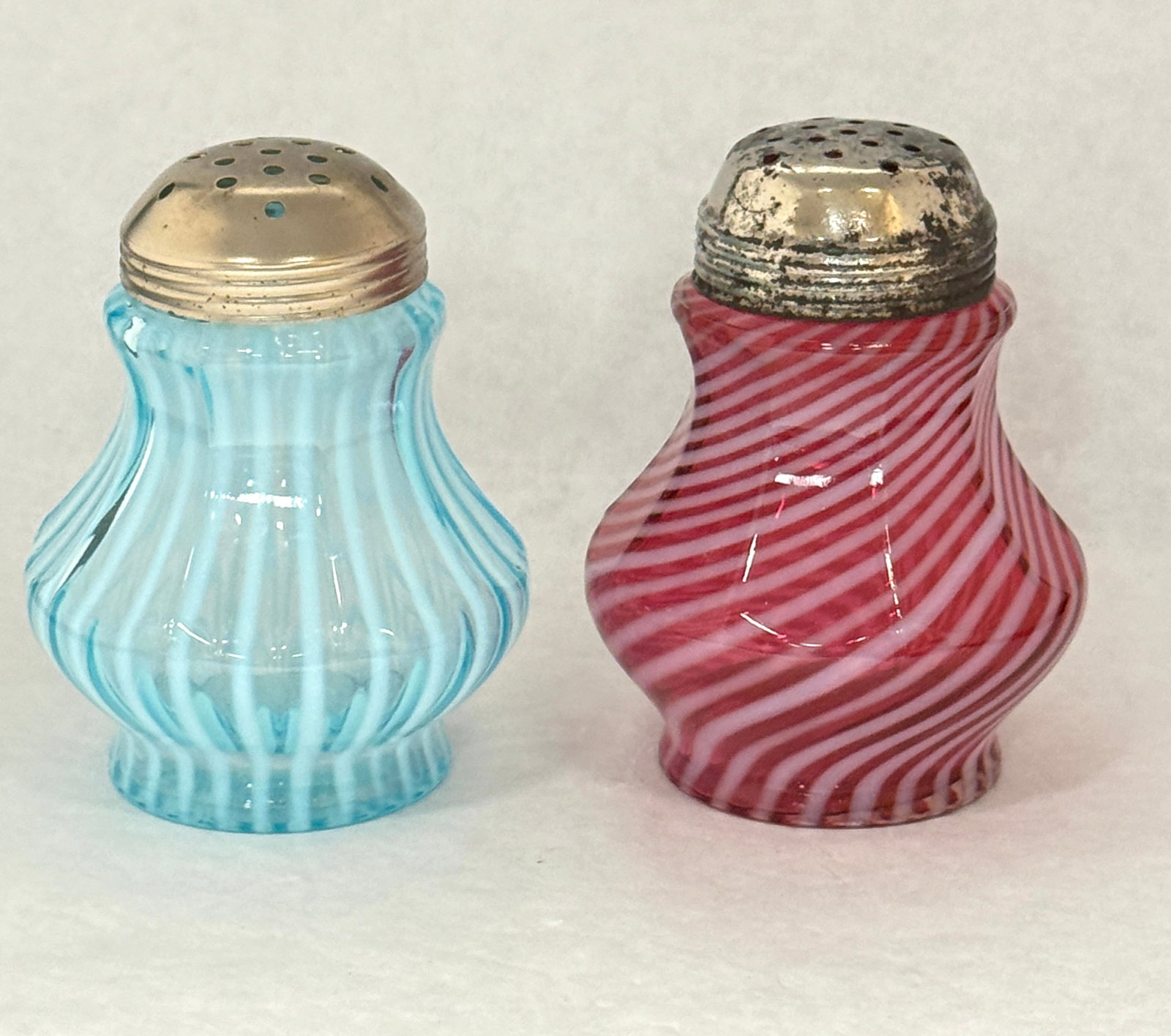 2 9 Panel Sugar Shakers: 2 9 panel sugar shakers one in cranberry swirl and 1 blue stripe; ht. 5". CONDITION: no chips, cracks, repairs, or material defects found, Jaremos attempts to call any material flaw that affects the p