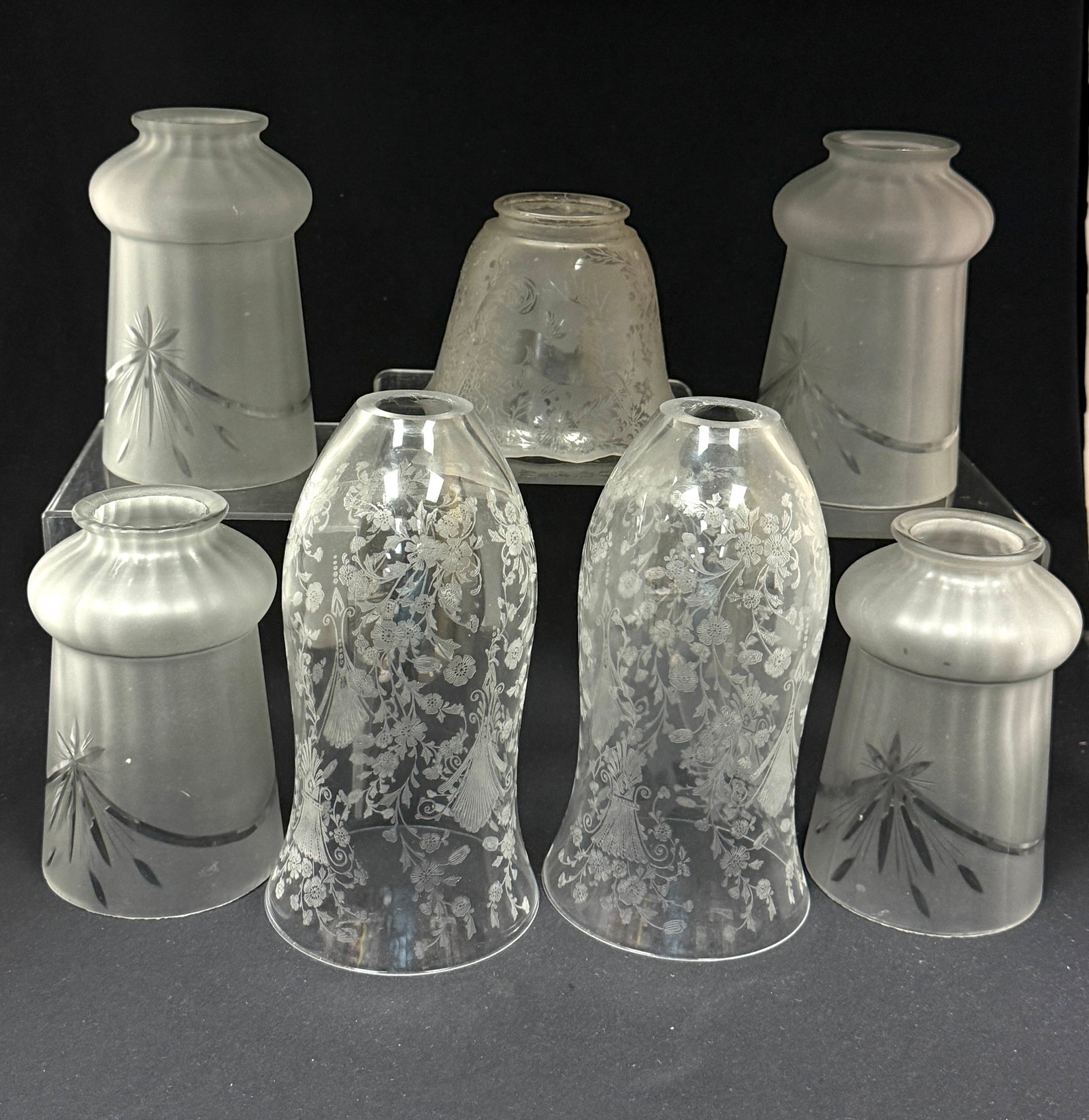 7 Shades: 7 shades of various styles 2 elongated torchiere etched with flowers and tassels, 1 short etched with deer, and 4 frosted and etched matching; longest 7 1/2", fitter 2 1/4". CONDITION: no chips,